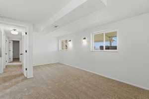 Carpeted room featuring white walls, two wall-mounted sconces, and a white-framed window