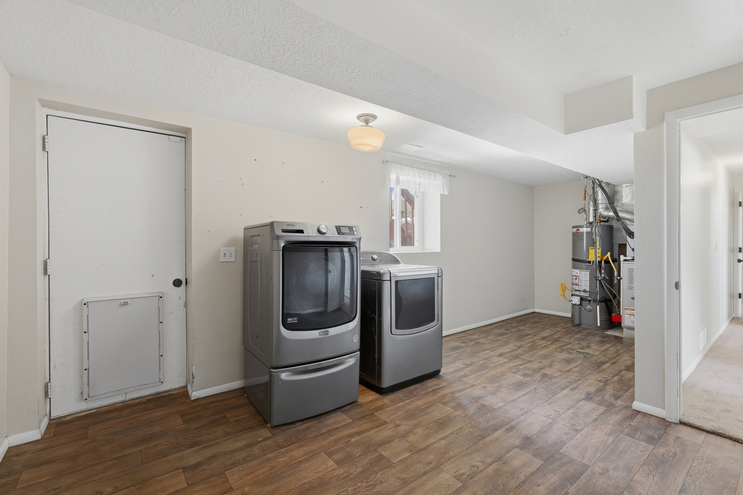 Utility area featuring wood-finish flooring, a window with white trim, and a ceiling-mounted light fixture