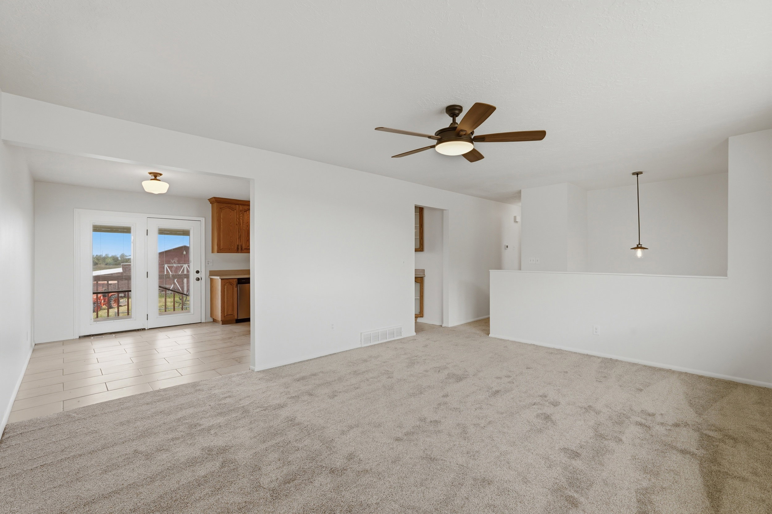 Spacious living area featuring neutral carpeting and a ceiling fan with integrated lighting