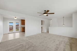 Spacious living area featuring neutral carpeting and a ceiling fan with integrated lighting