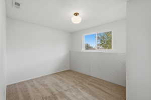 Bright room featuring a window, textured wall paneling, neutral carpet, and a ceiling-mounted light fixture