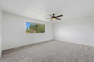 Spacious room with light gray carpeting, neutral white walls, and a large window