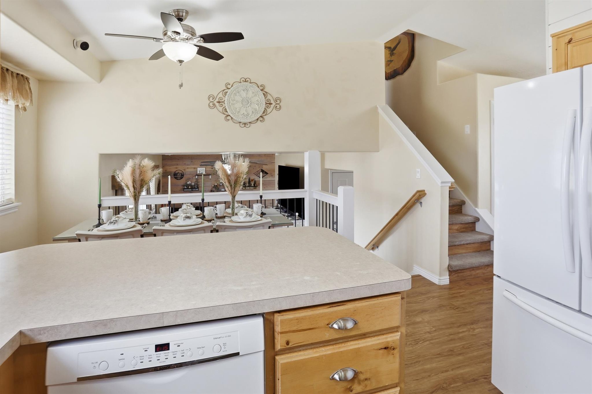 Kitchen peninsula with a light-toned countertop, integrated dishwasher, and wood-finish cabinetry