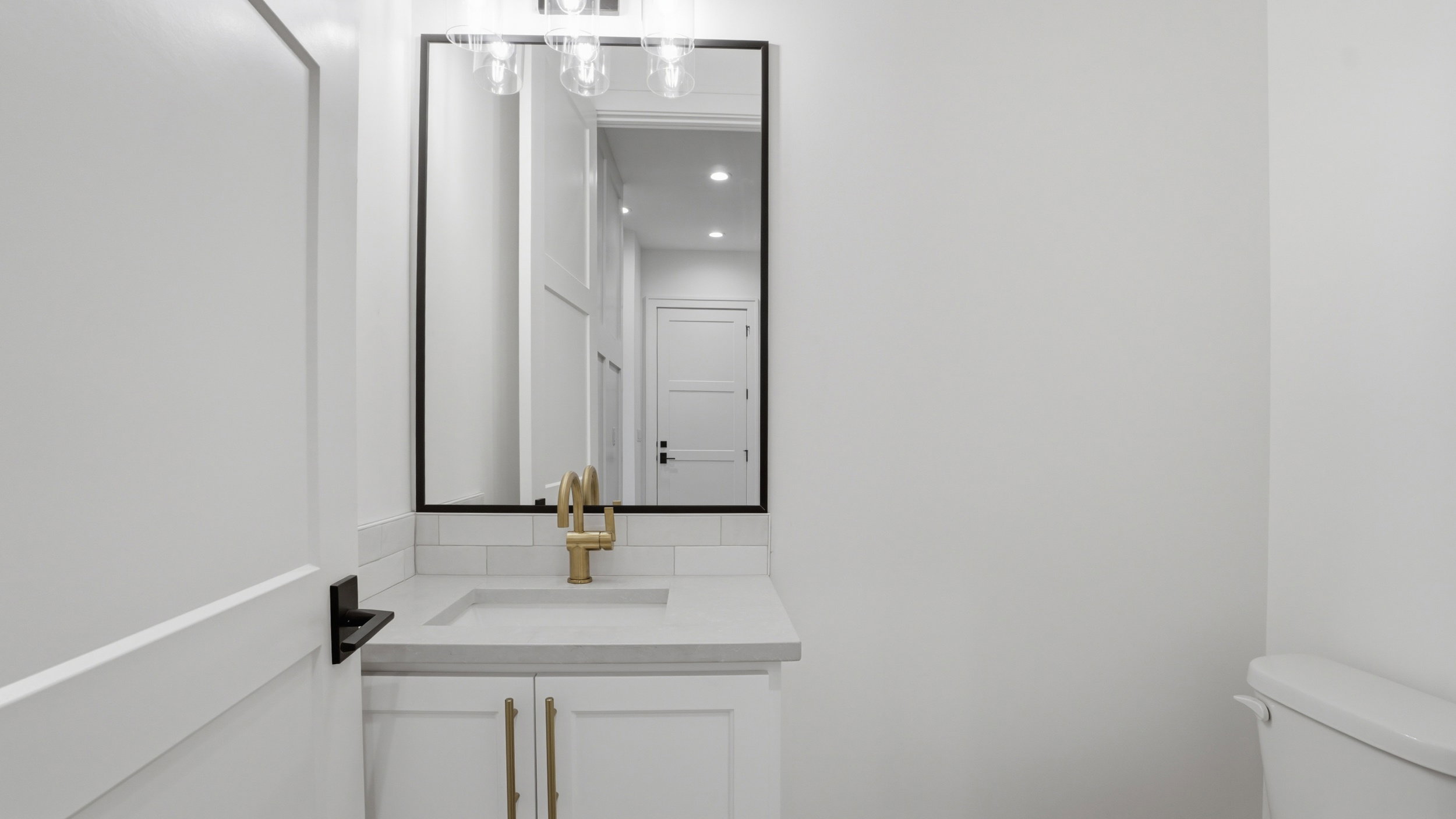 Bathroom vanity featuring a rectangular undermount sink, brass-finish faucet, and coordinating cabinet hardware
