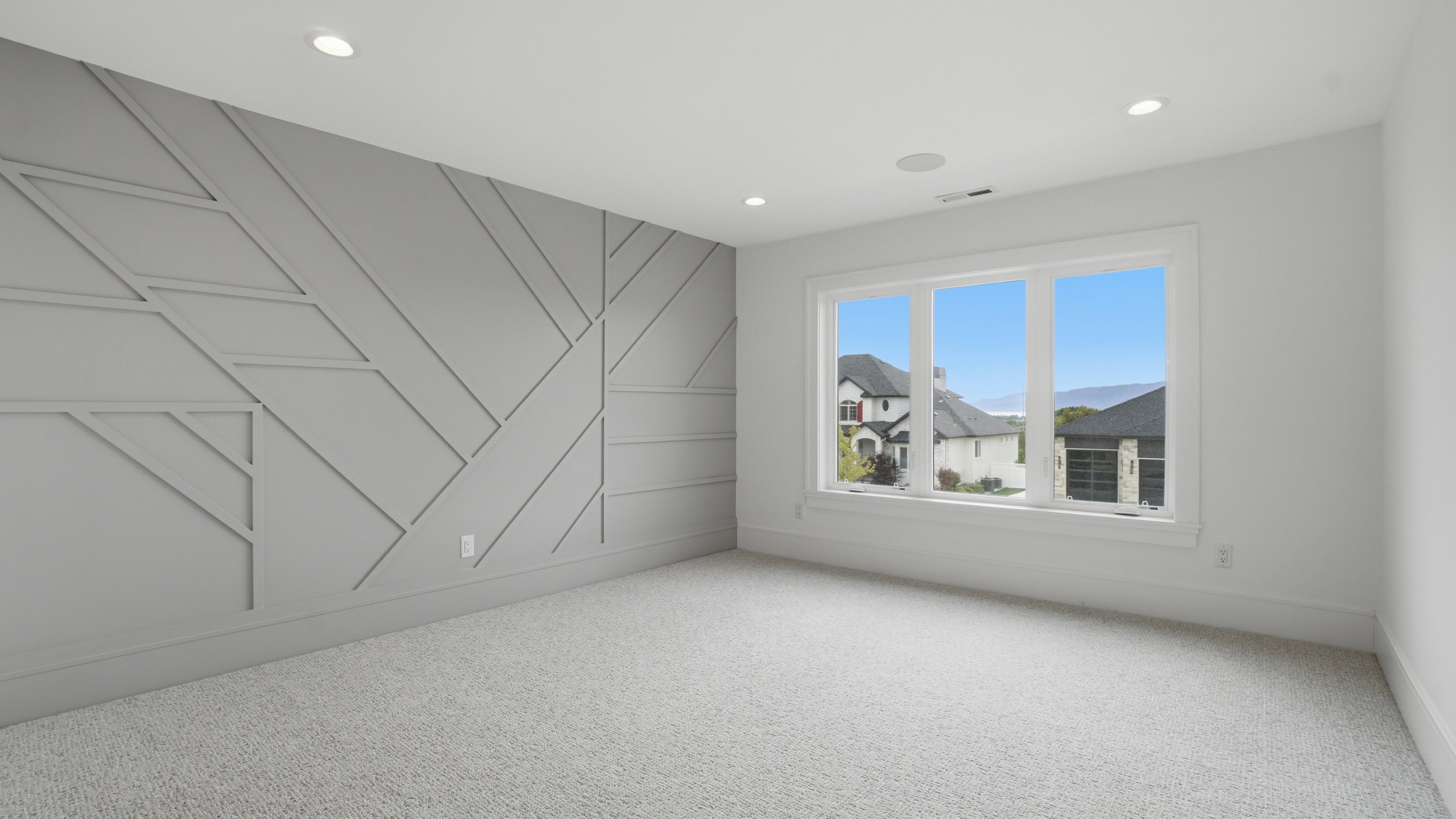 Room featuring a textured accent wall with geometric molding, recessed lighting, and light-colored carpeting