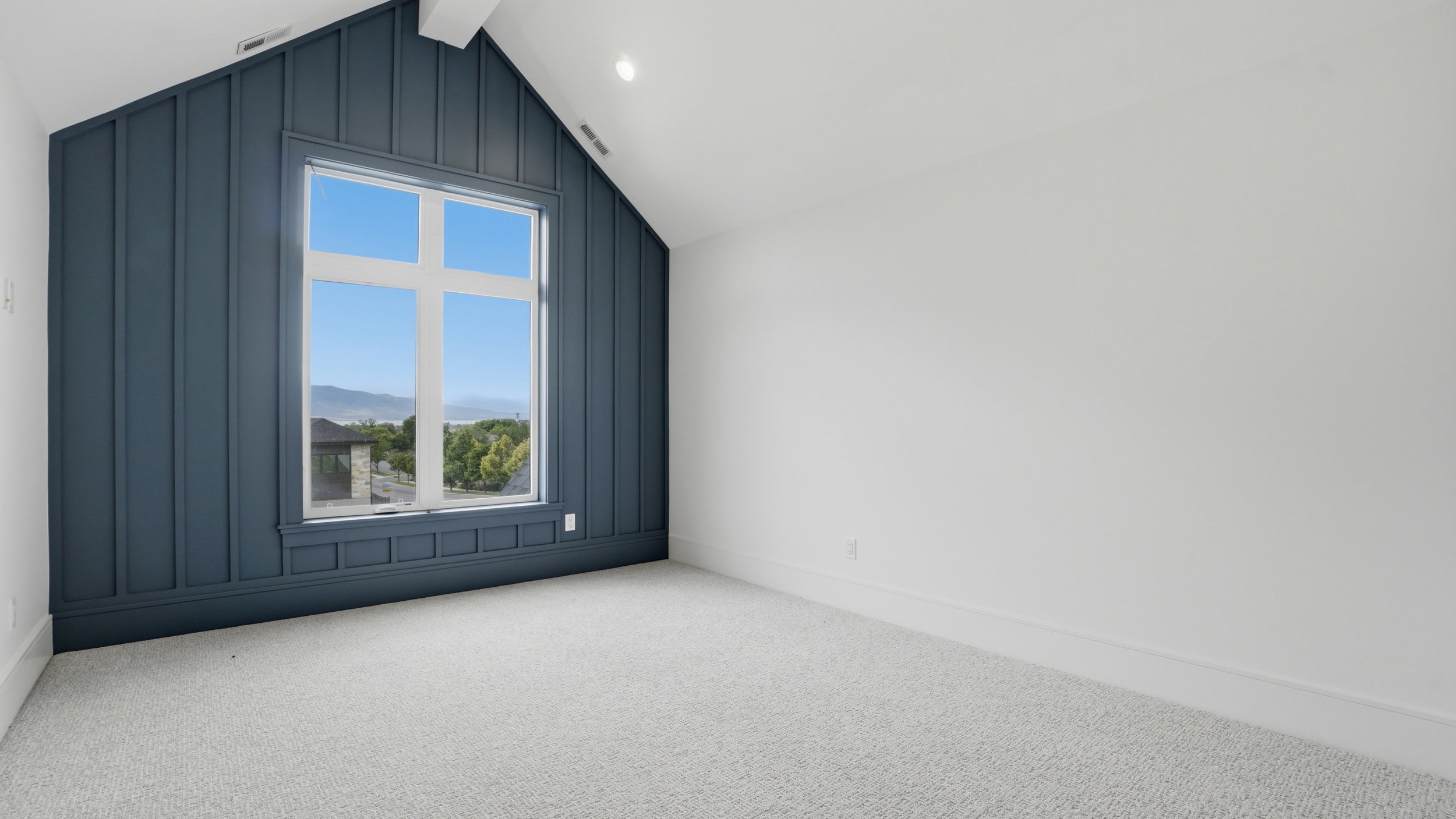 Room featuring a prominent accent wall with vertical paneling and an integrated large window