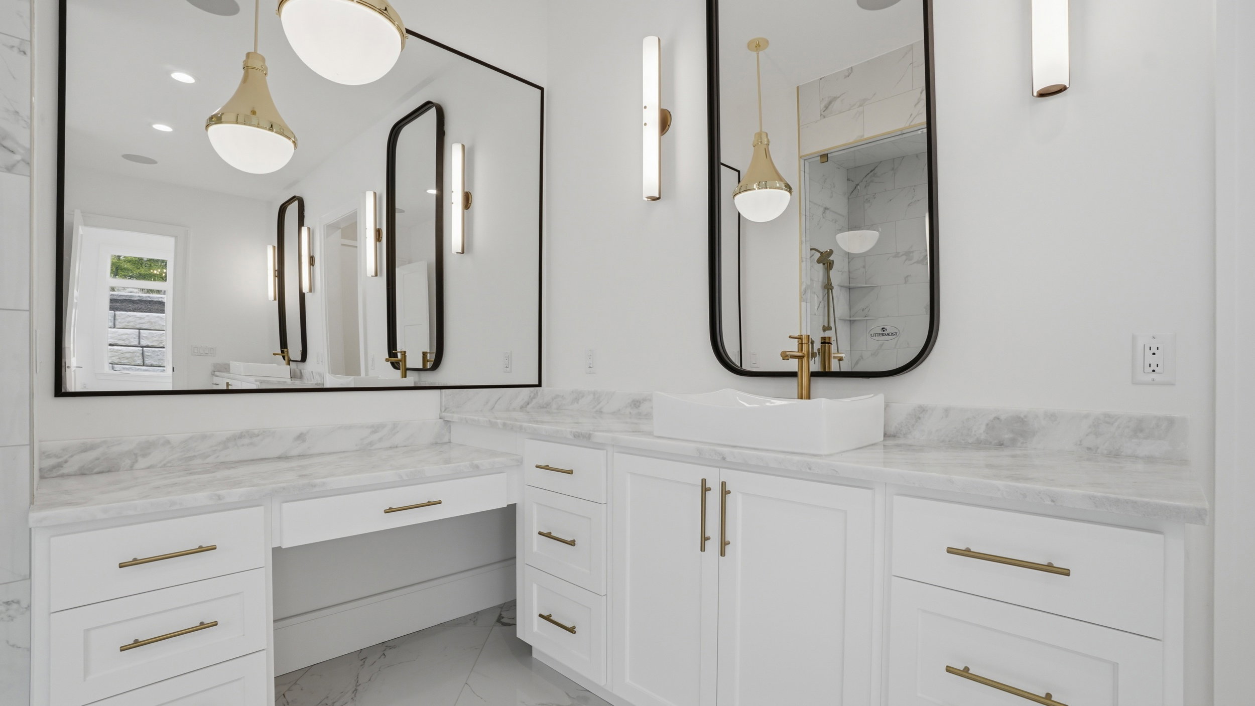 Bathroom vanity featuring white cabinetry with brass hardware, a contrasting white vessel sink, and a large wall-mounted mirror