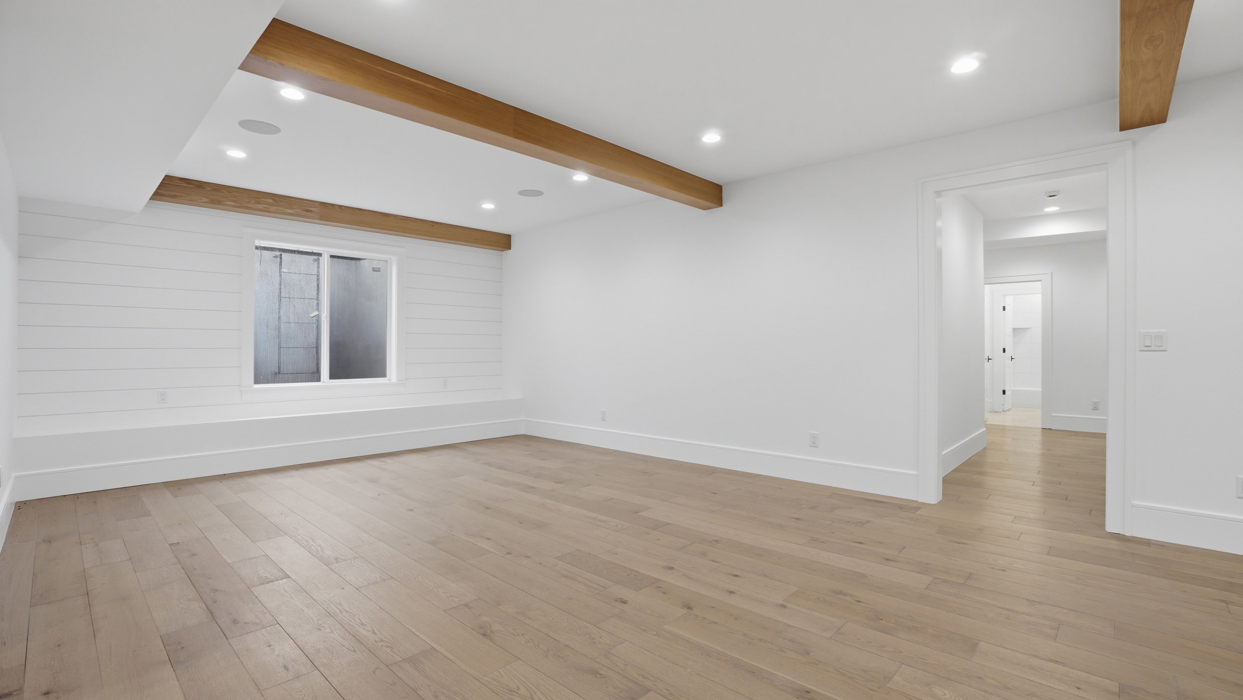 Spacious room featuring wood-finish flooring, recessed lighting, and exposed ceiling beams