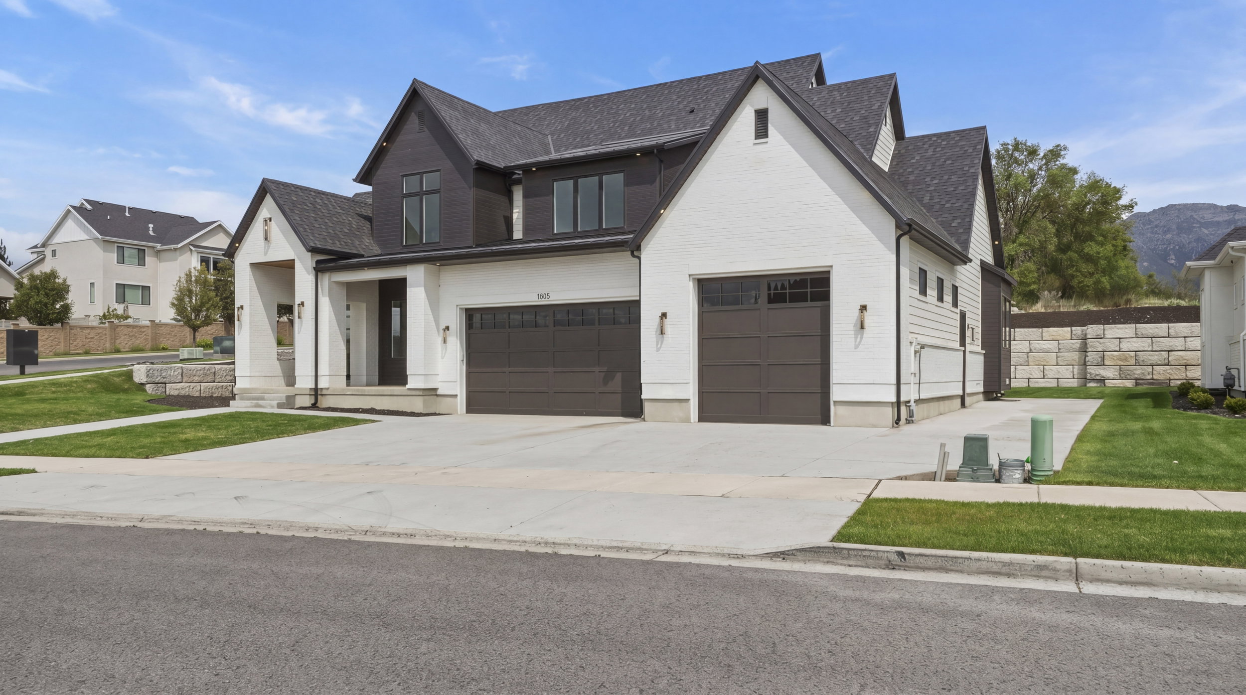 Modern farmhouse-style exterior featuring white siding, dark trim, and a dark shingle roof