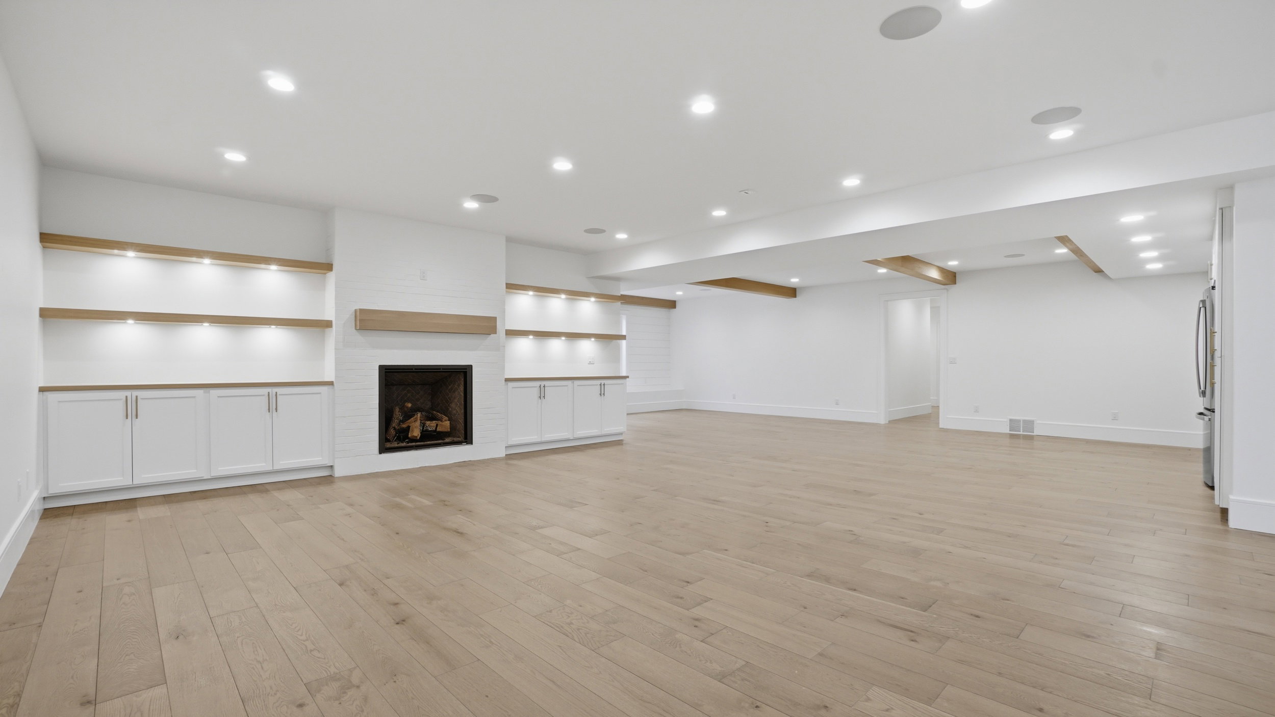 Spacious room featuring wood-finish flooring, recessed lighting, and white walls