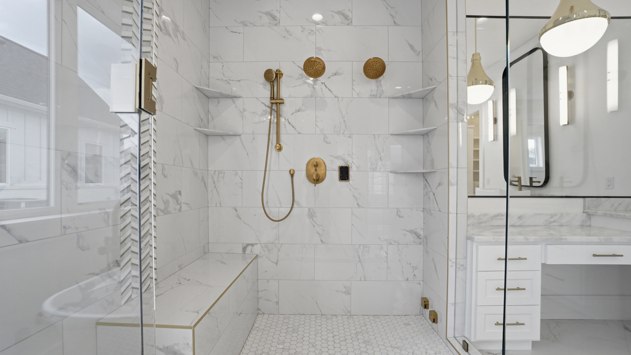 Walk-in shower with full height stone-look tile, hexagonal floor tile, built-in bench with gold-tone trim, and built-in shelving