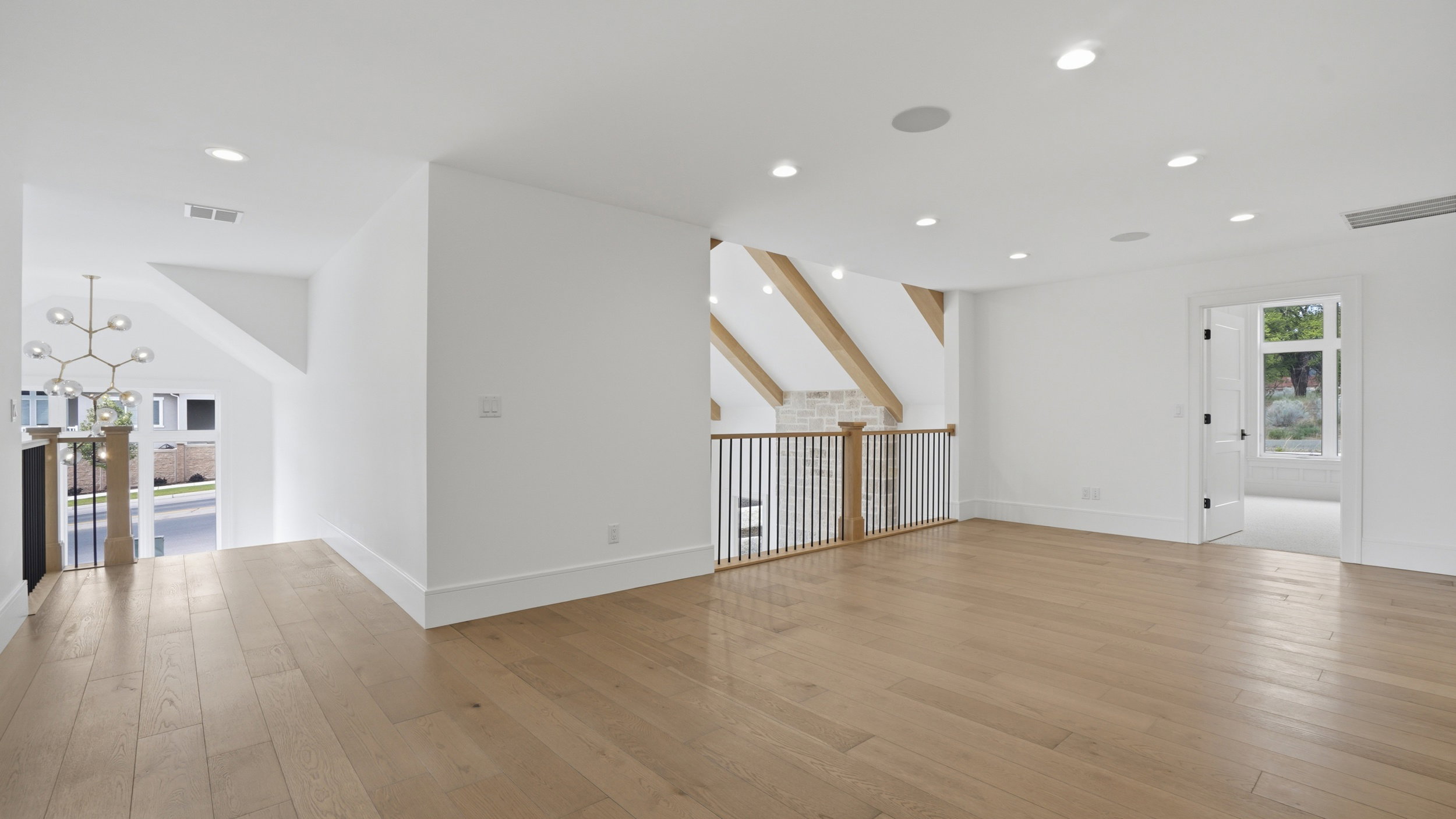 Spacious upper-level area featuring wood-finish flooring, recessed lighting, and a modern chandelier