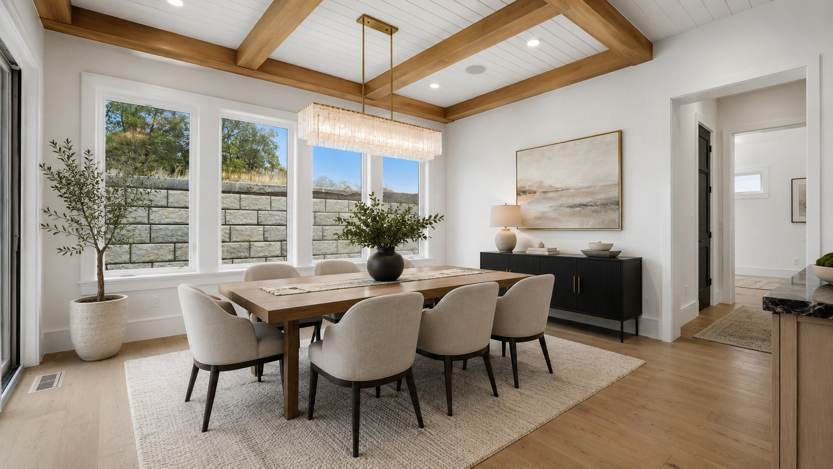 Dining area featuring a coffered ceiling with wood beams, a contemporary linear chandelier, wide-plank wood-finish flooring, and multiple large windows