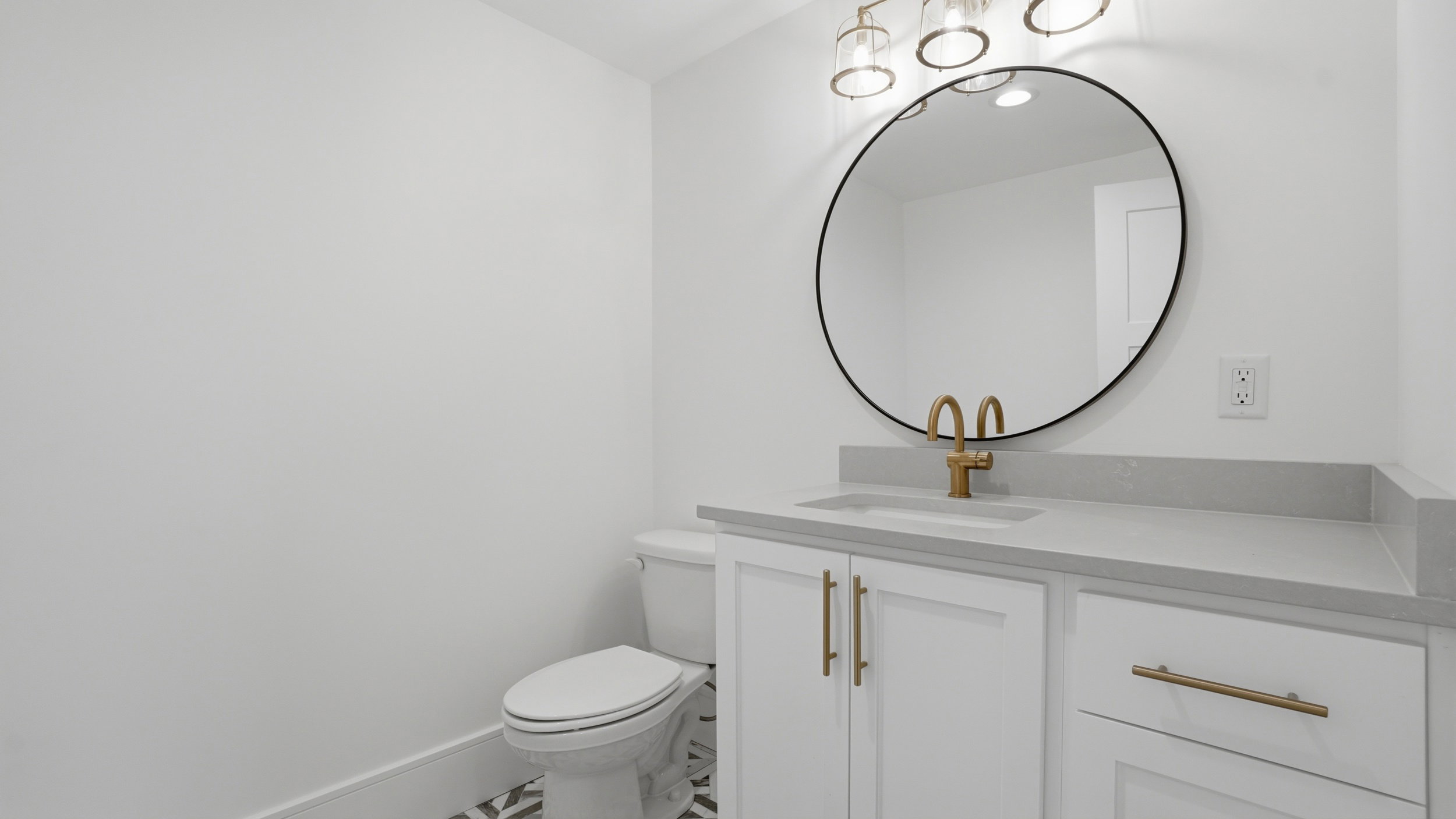 Vanity featuring a built-in sink, light gray countertop, and white cabinetry with gold-finish hardware