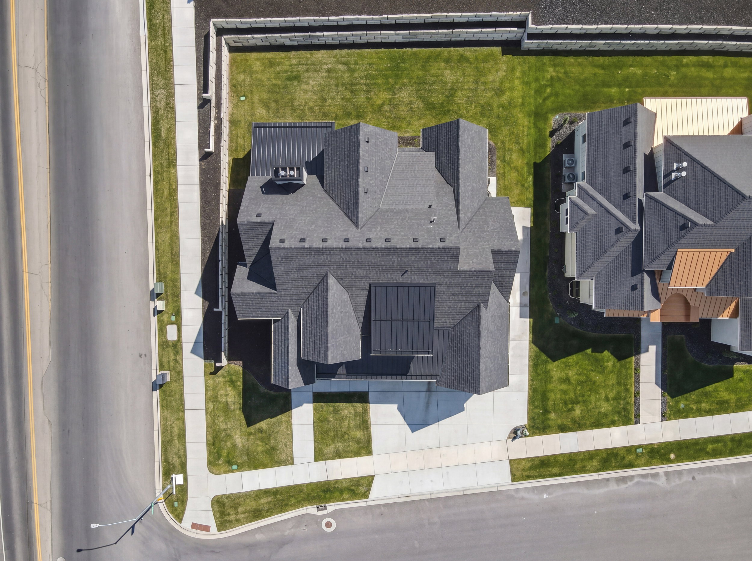 Modern residential property featuring a multi-gabled dark shingle roof with integrated solar panels and a contrasting dark metal roof section