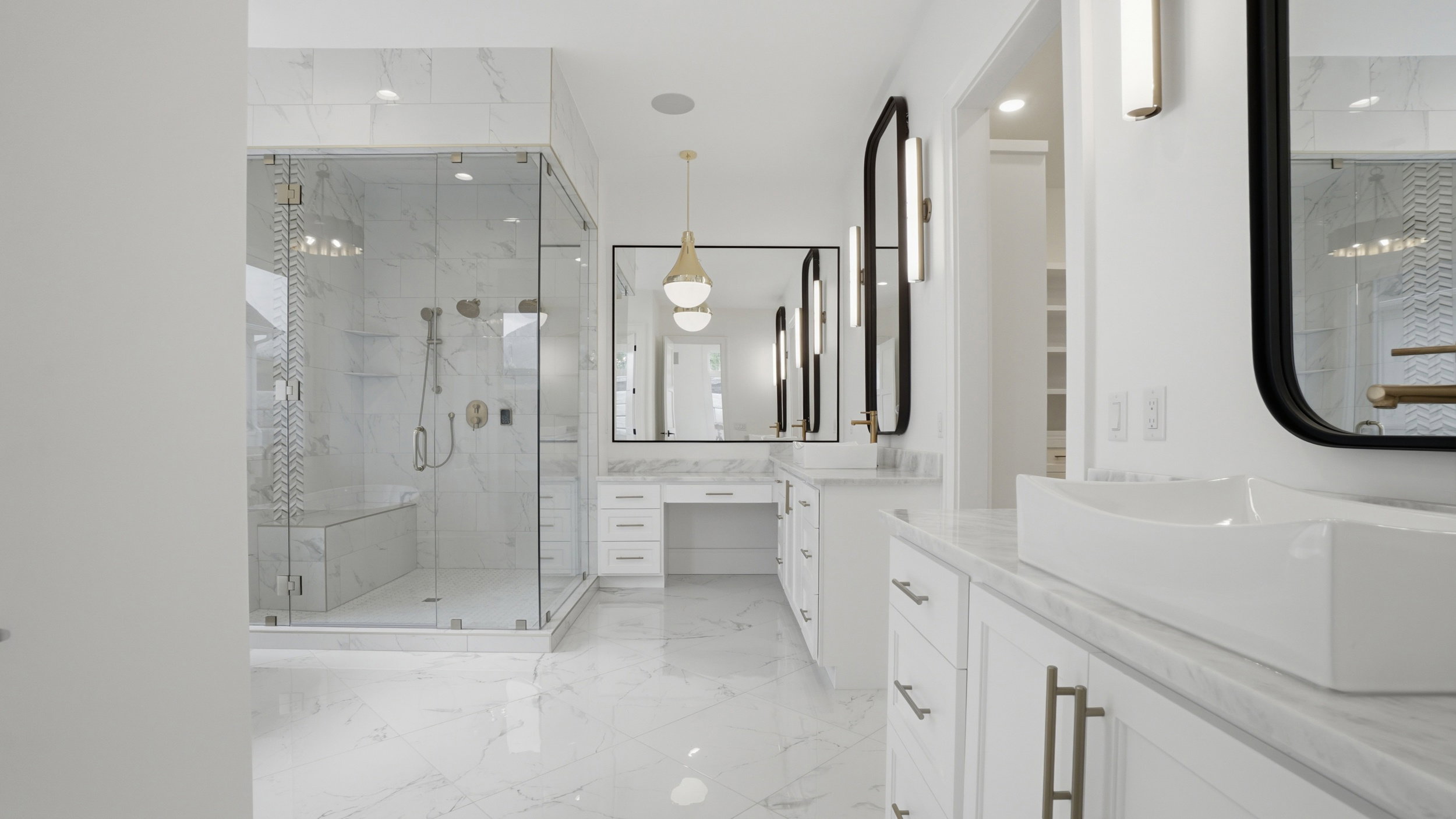 Spacious bathroom featuring a frameless glass shower enclosure with bench seating, dual vanity with vessel sinks, white cabinetry, and large format tiled flooring