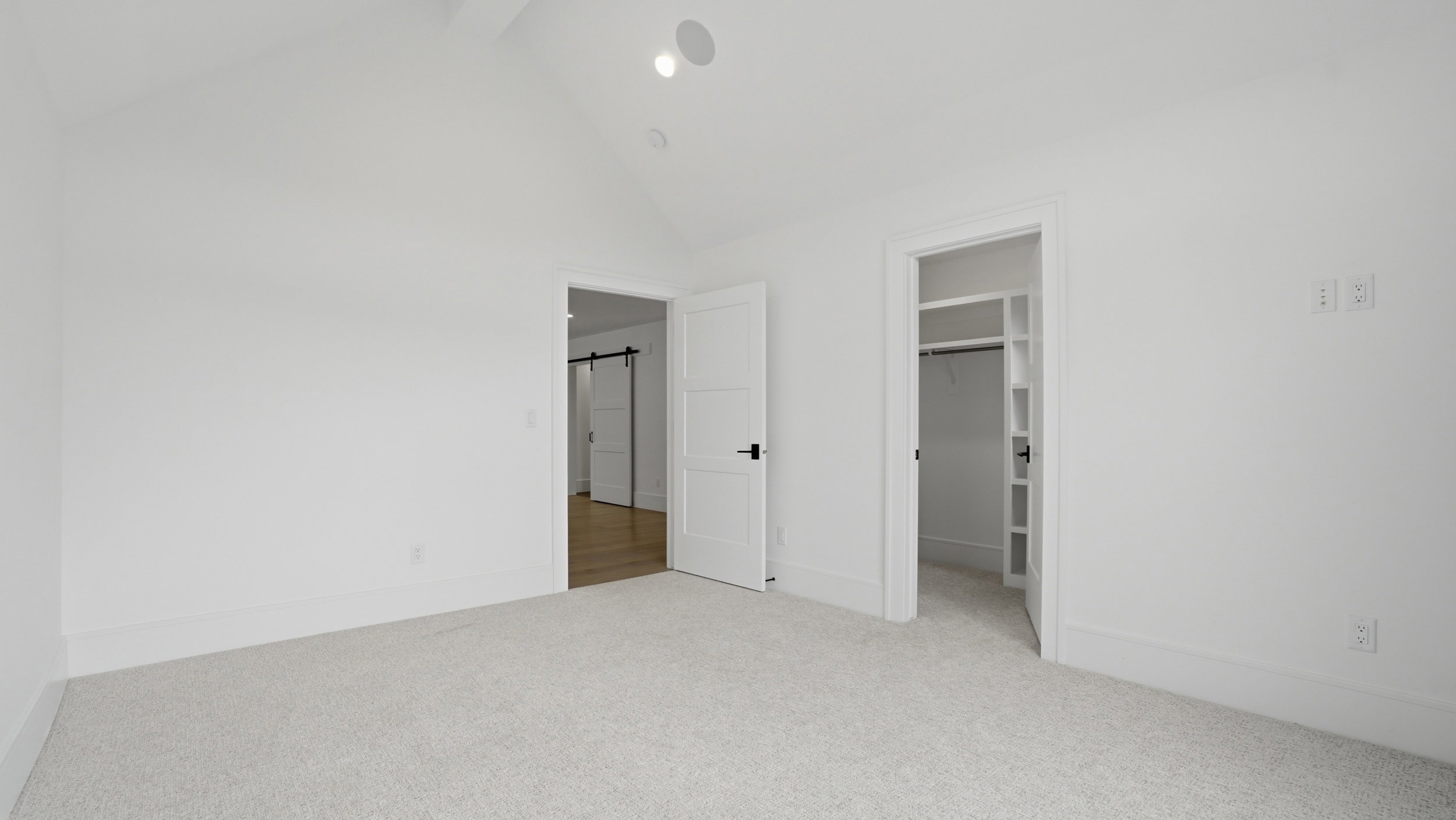 Carpeted room with a vaulted ceiling, recessed lighting, and a built-in closet with shelving