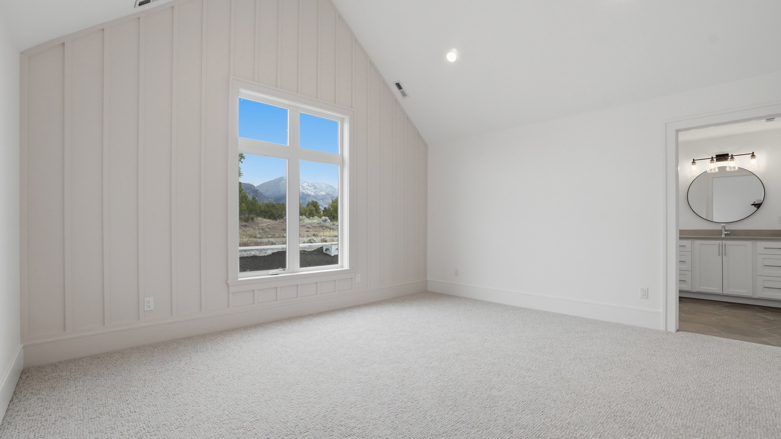 Spacious room featuring vaulted ceilings, board and batten wall detailing, and a large picture window