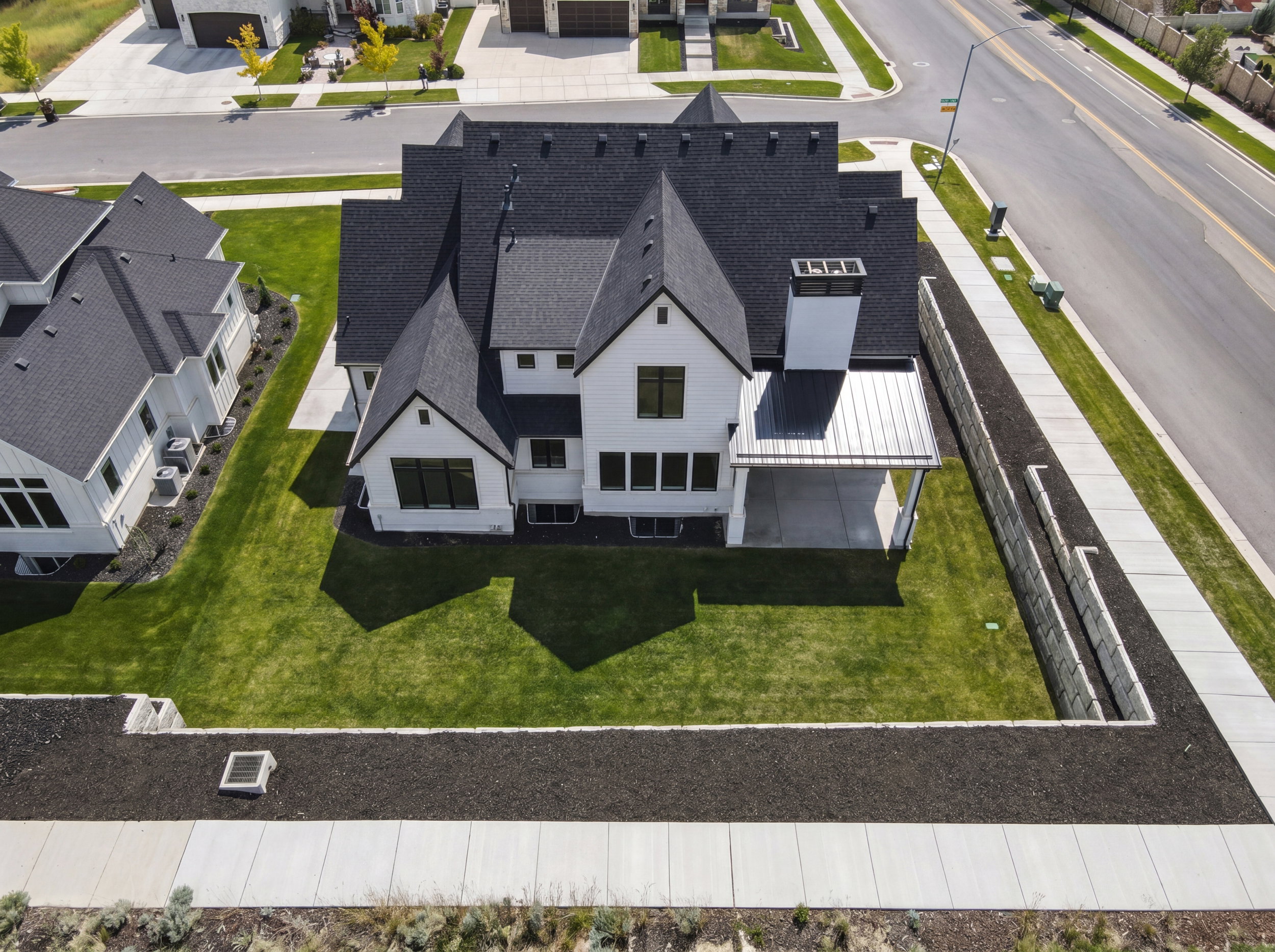 Contemporary white exterior with dark-framed windows, a covered patio, a prominent chimney feature, and a newly laid asphalt roof