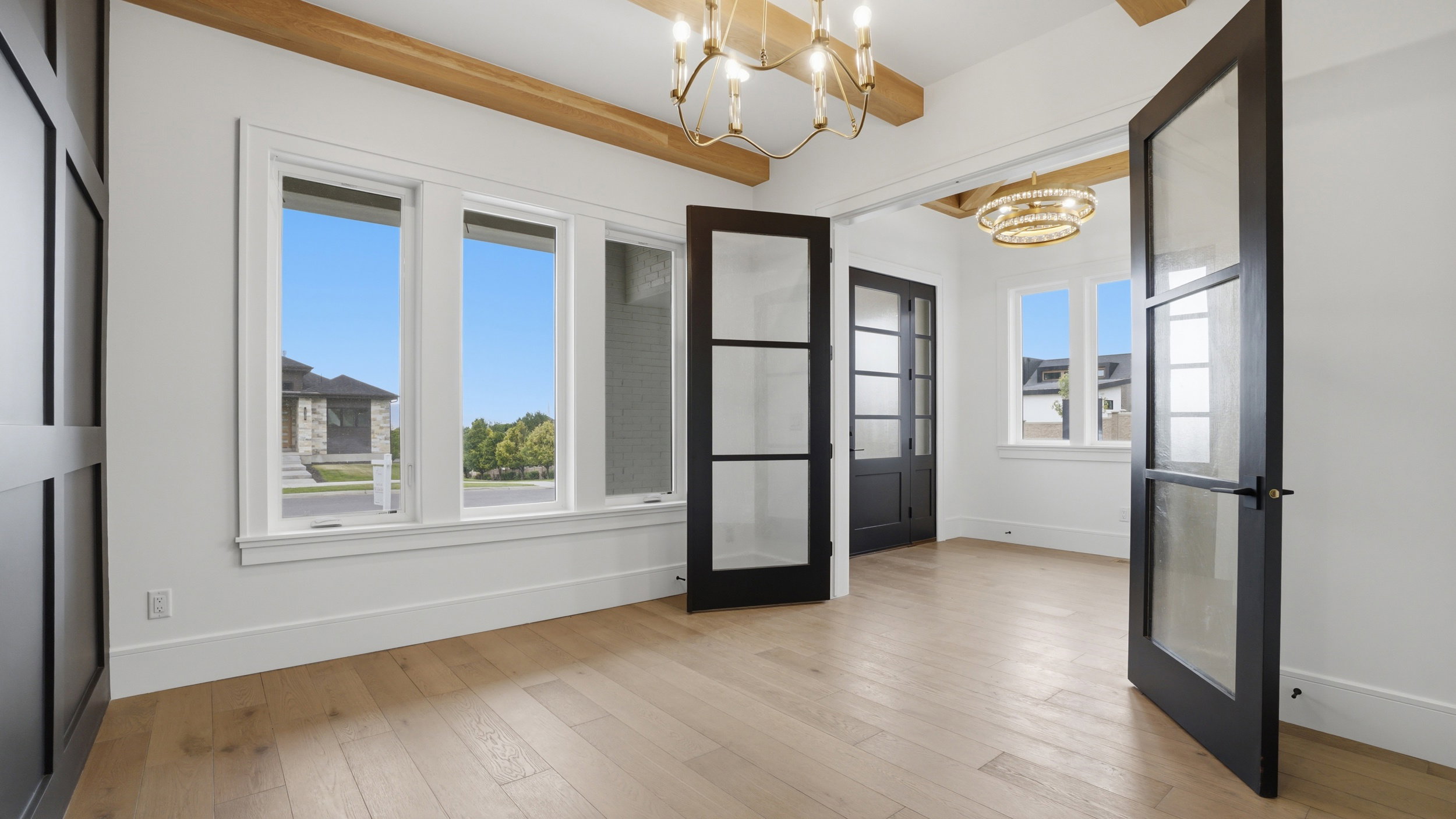 Room featuring wood-finish flooring, exposed wood beams, and multiple windows