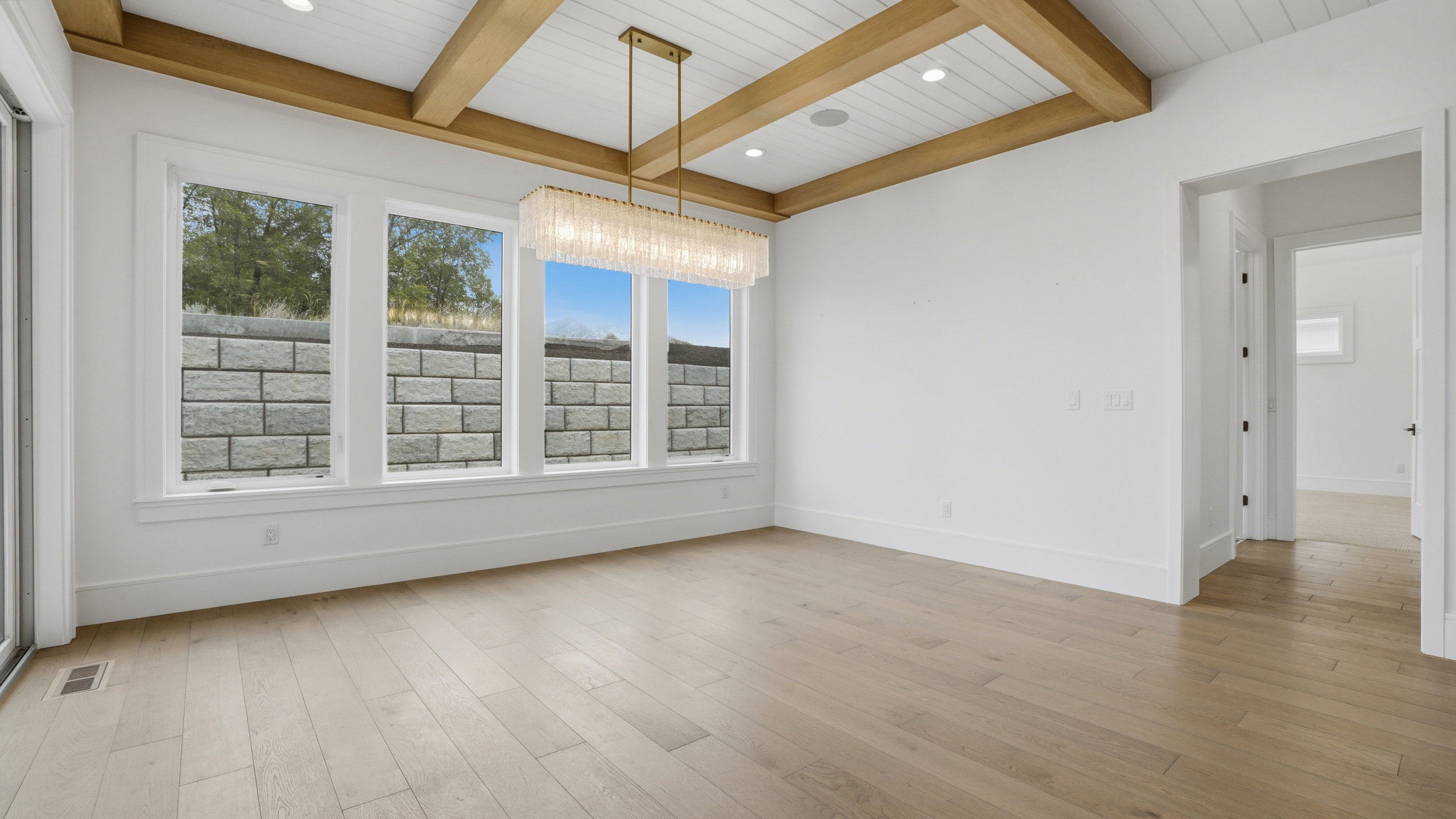 Spacious interior featuring wide plank wood-finish flooring, a beamed and shiplap ceiling, recessed lighting, and a linear chandelier
