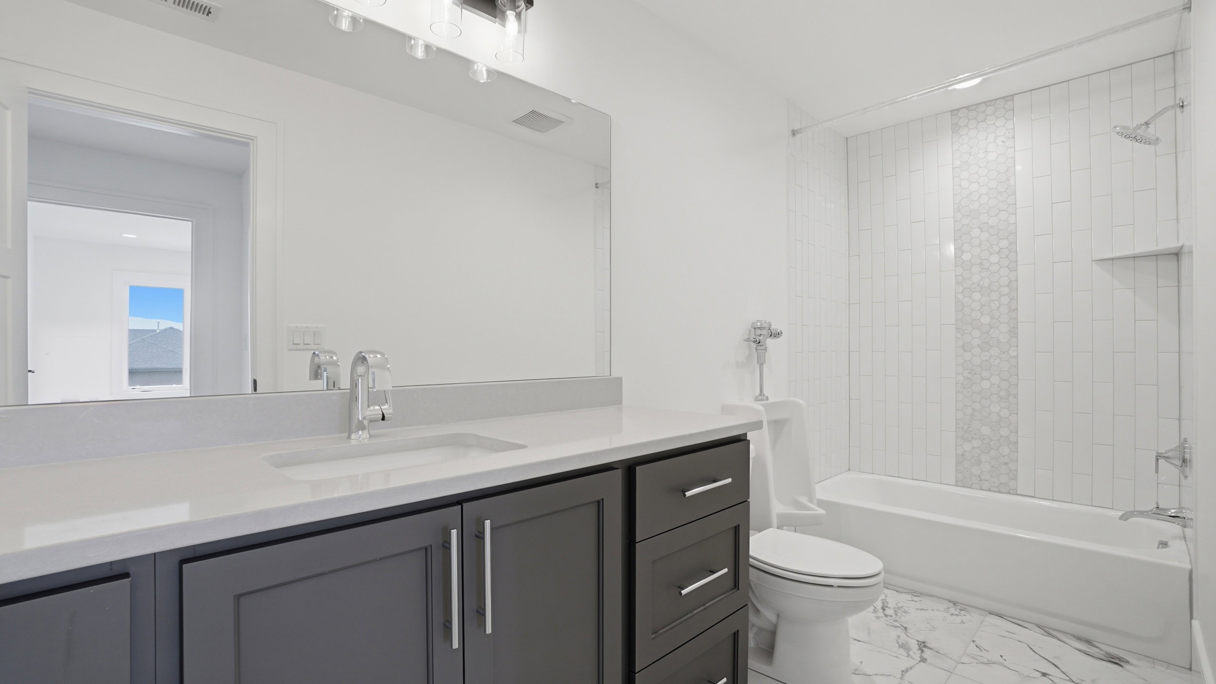 Bathroom featuring a gray vanity with a single under-mount sink, white countertop, and a large wall-mounted mirror