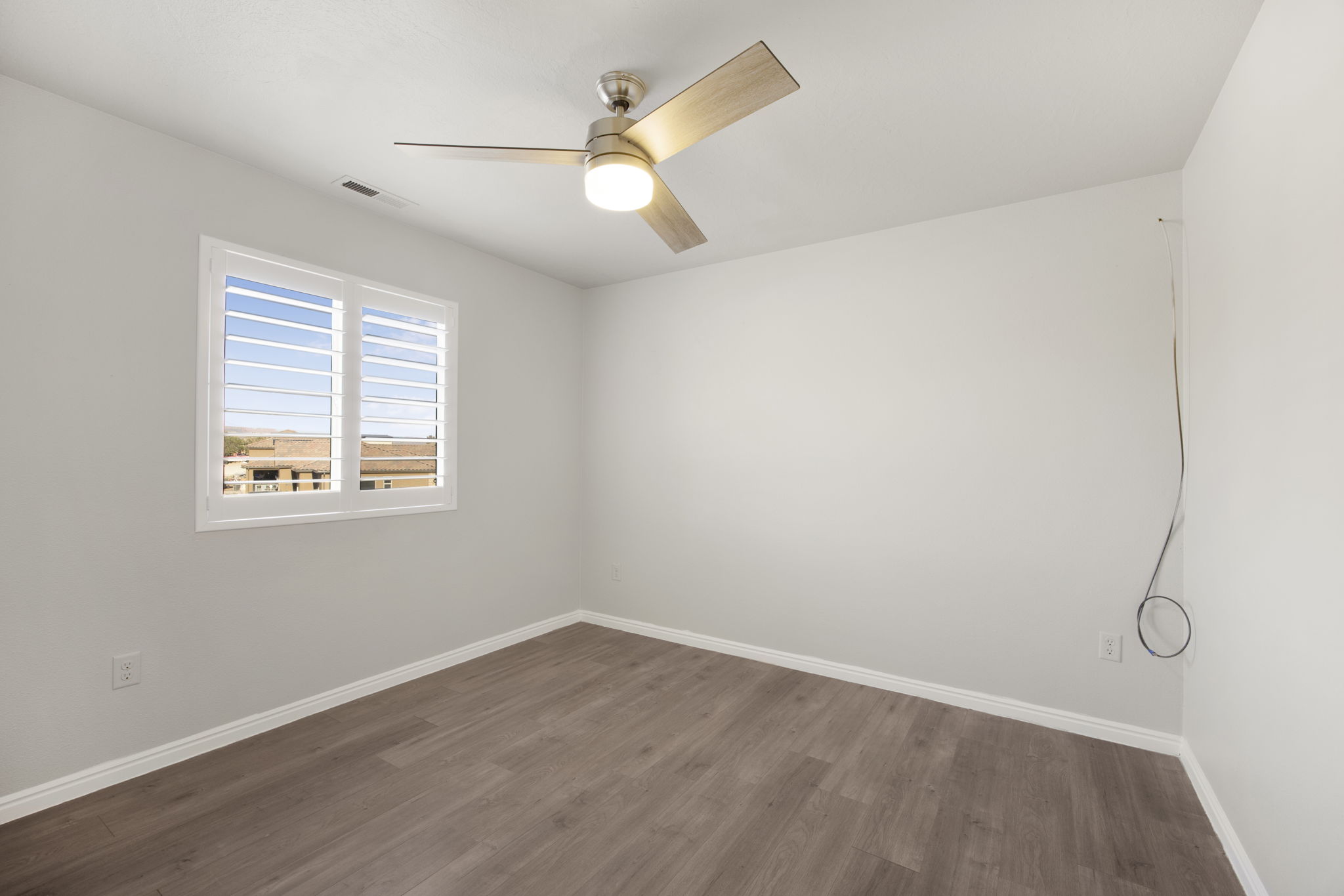 Neutral wall paint with wood-finish flooring, featuring a ceiling fan with integrated lighting