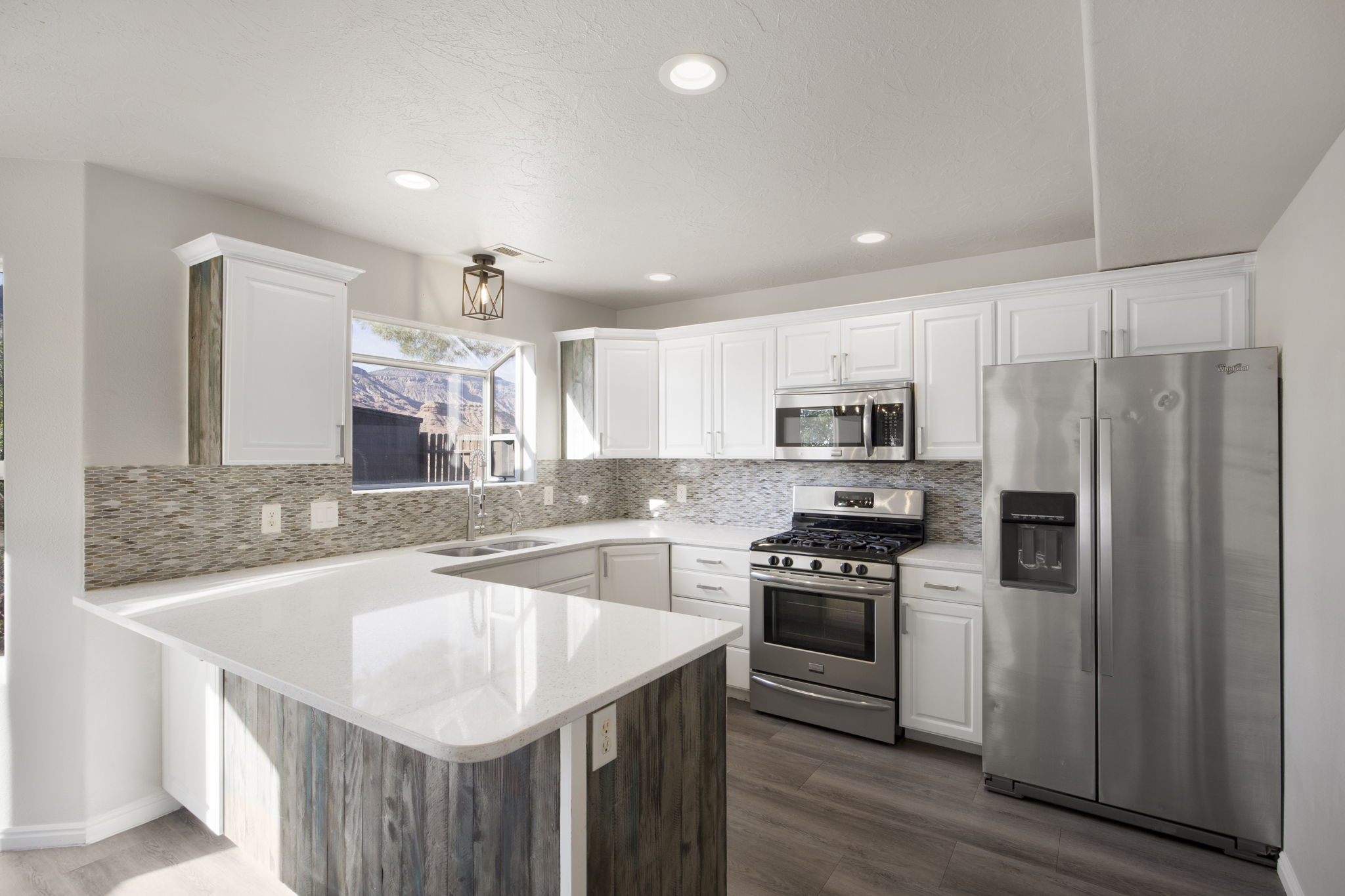 Modern kitchen featuring white cabinetry, light-toned countertops, a mosaic tile backsplash, stainless steel appliances, and wood-finish flooring