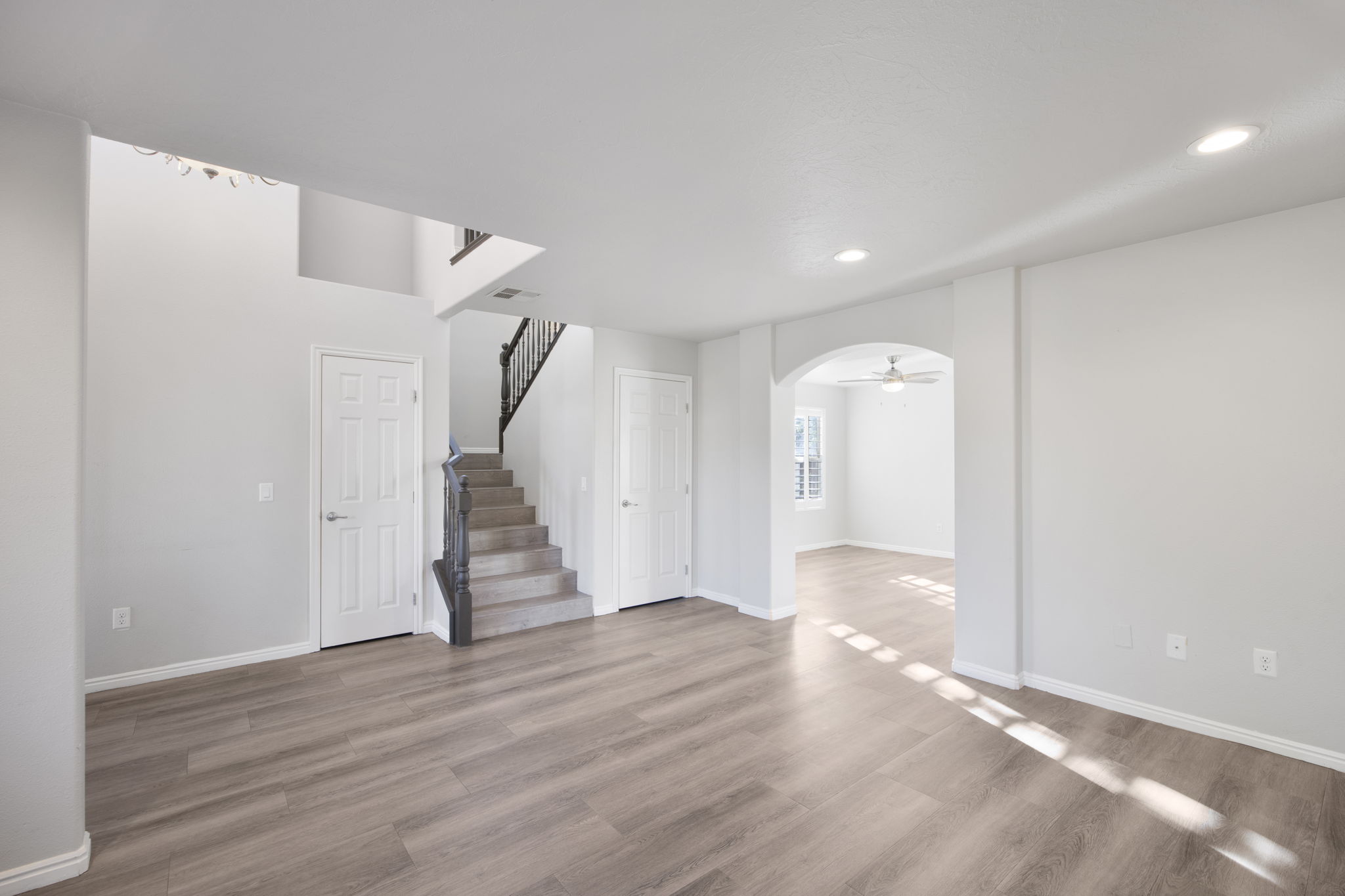 Spacious interior featuring wood-finish flooring, light gray wall tones, recessed lighting, and white baseboards