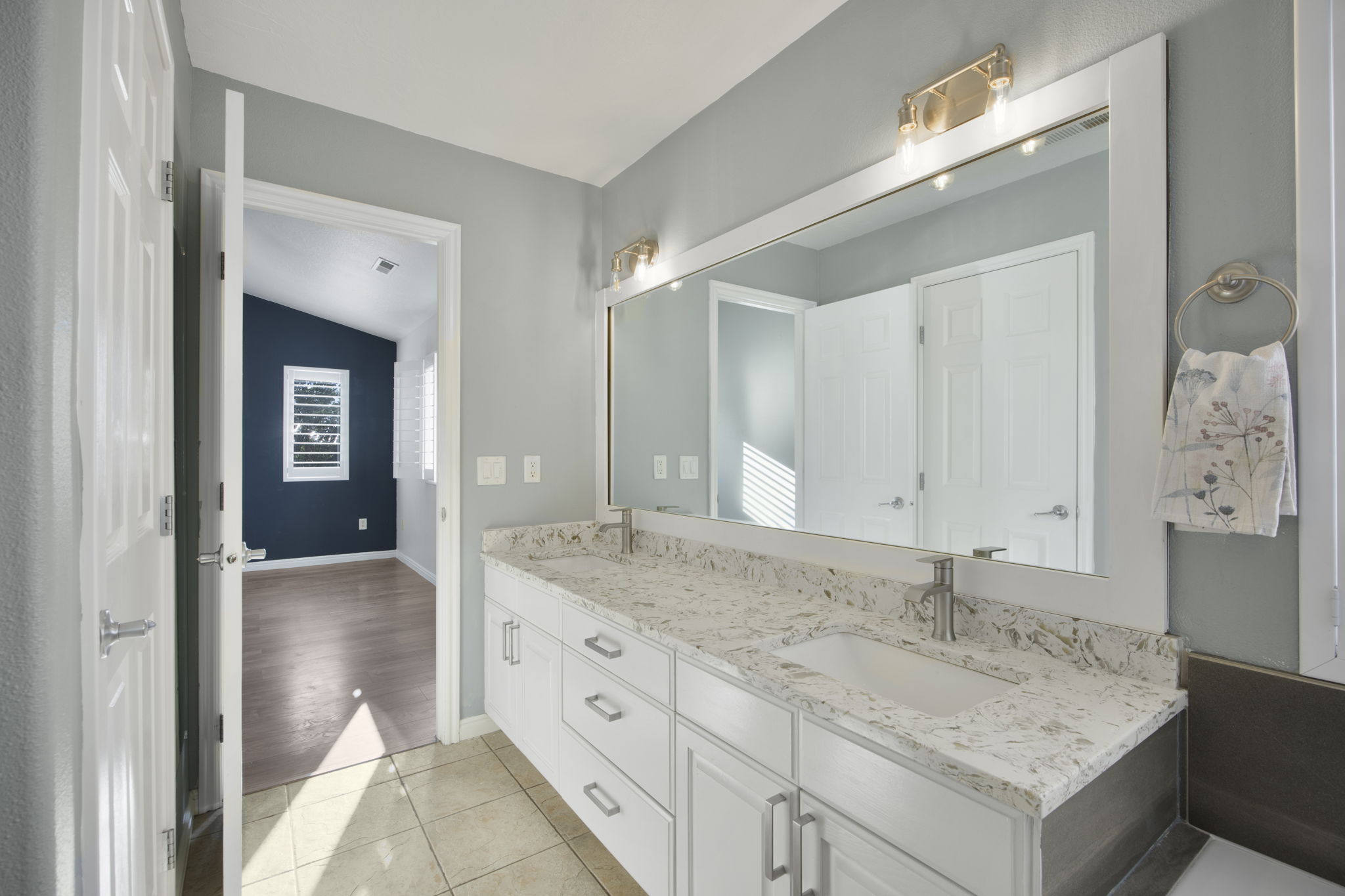 Dual vanity with white cabinetry and integrated sinks set beneath a large framed mirror