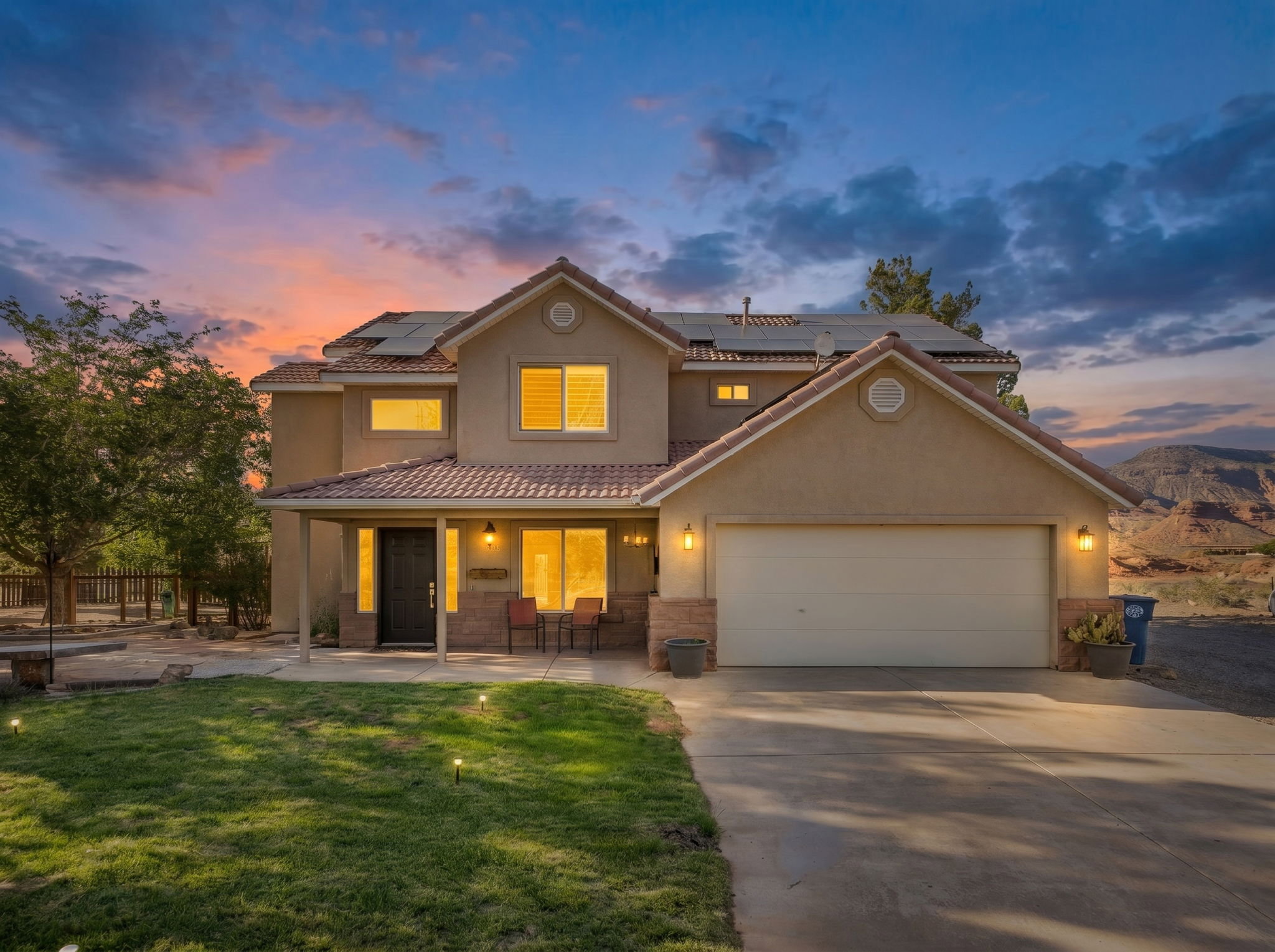Two-story residence featuring a terracotta-style roof, stucco exterior, and an attached two-car garage