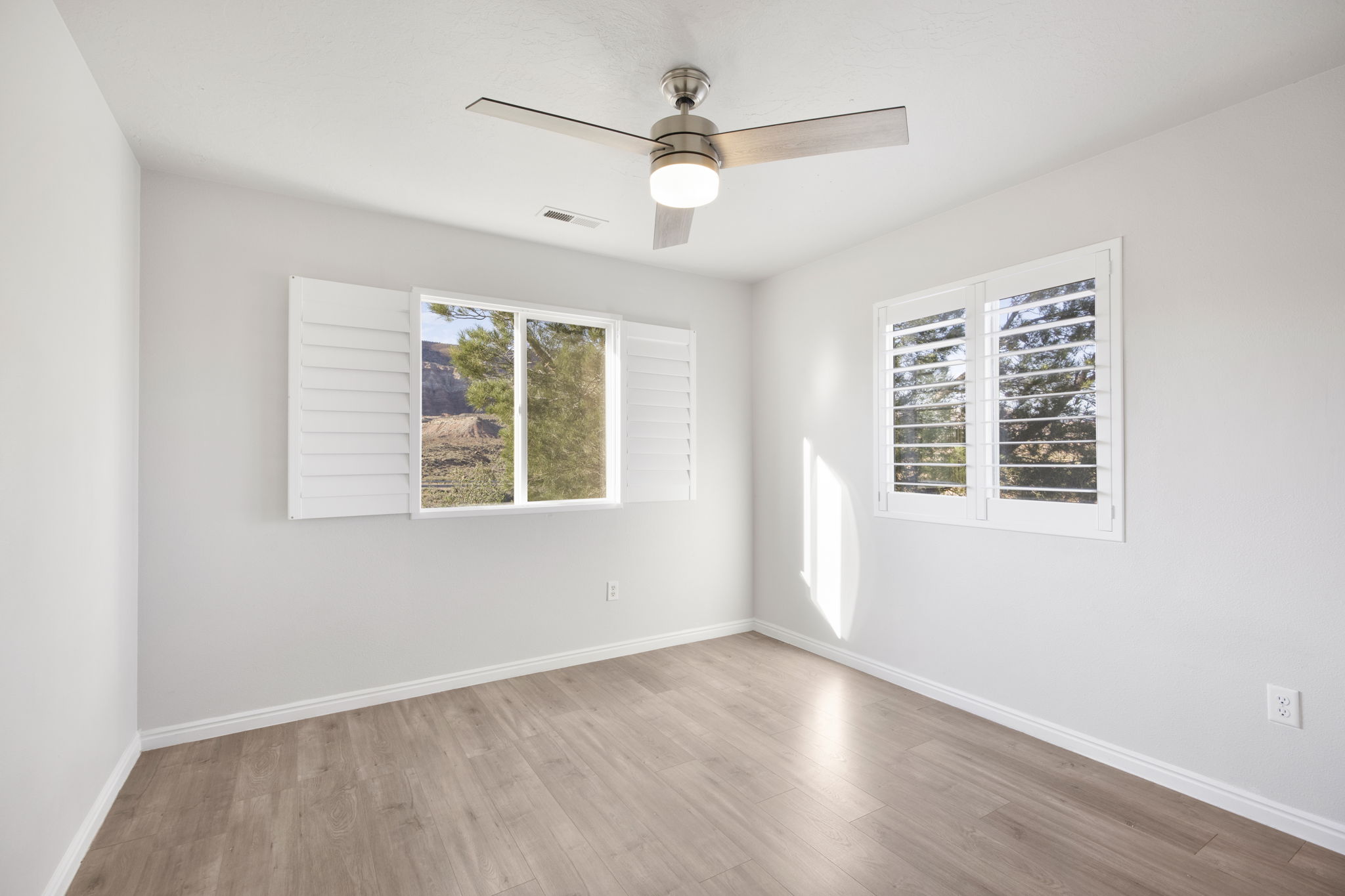 Spacious room featuring wood-finish flooring and light-toned walls