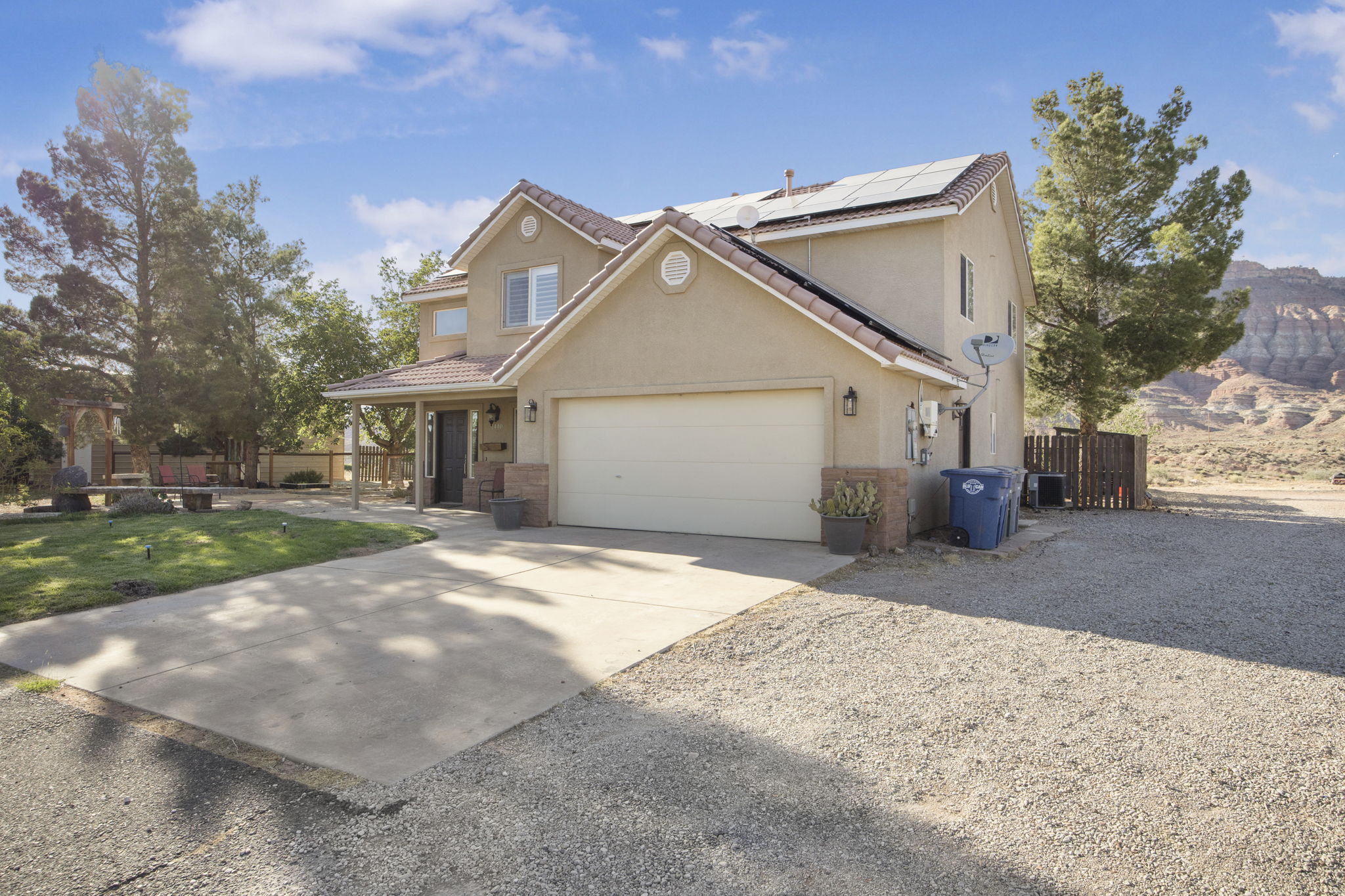 Two-story stucco residence featuring a covered entry porch, a two-car garage, and solar panels