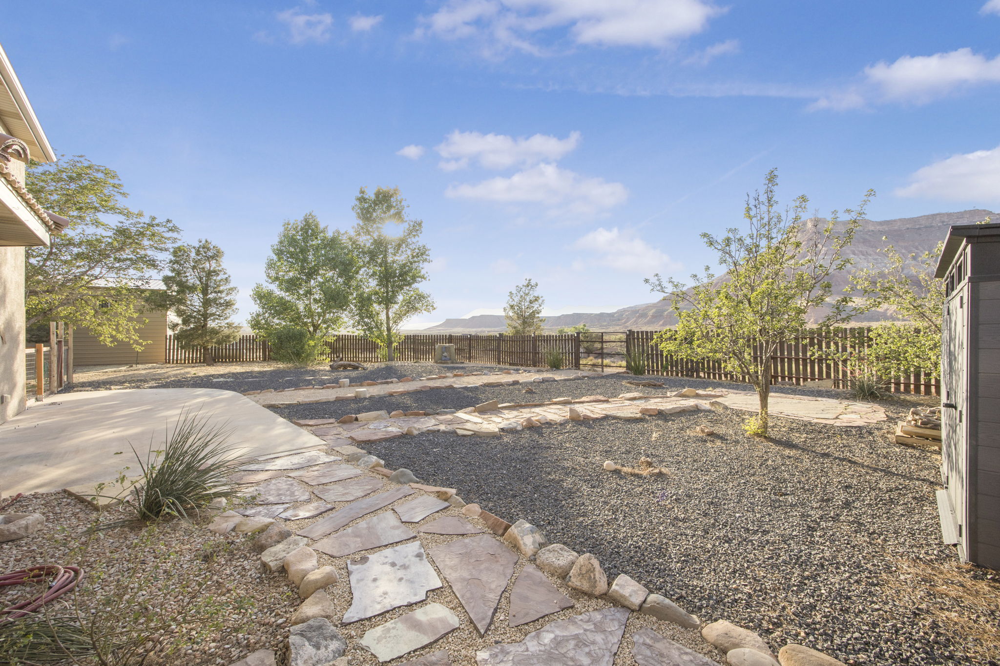 Expansive outdoor area featuring a concrete patio, flagstone pathway, and gravel landscaping