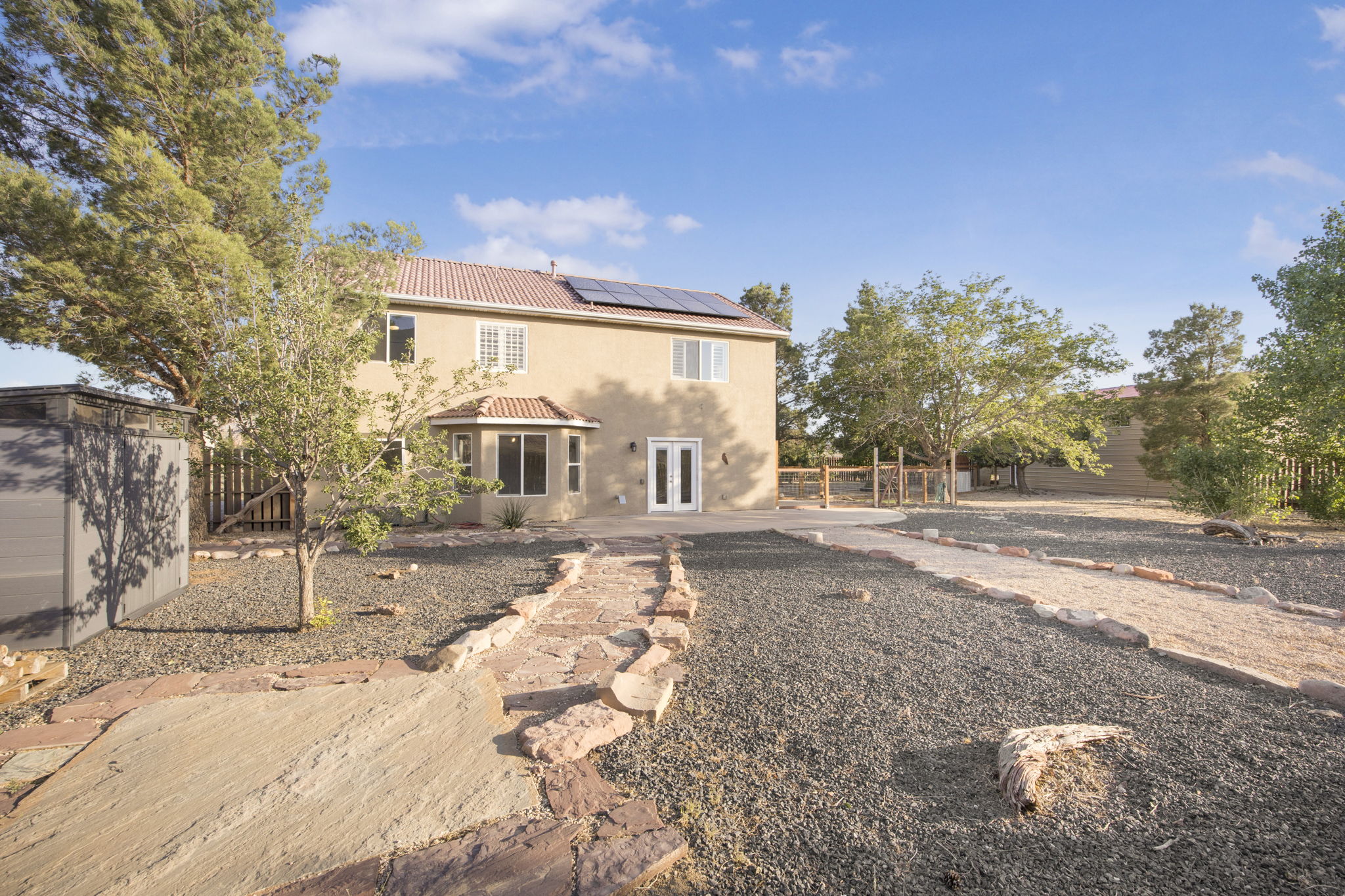 Spacious rear exterior featuring a neutral stucco facade, terracotta tile roof, and solar panels