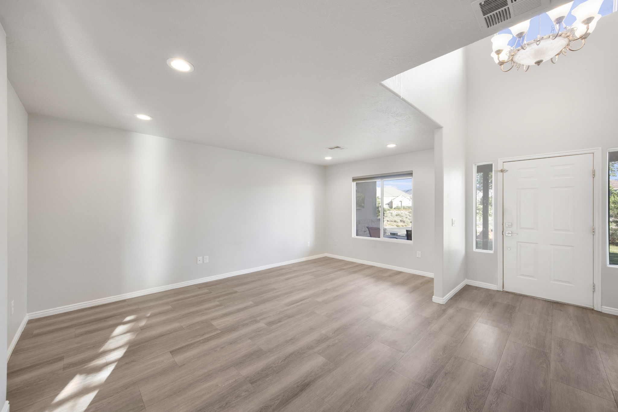 Entryway featuring a white paneled door with side lights, high ceilings, and a decorative chandelier