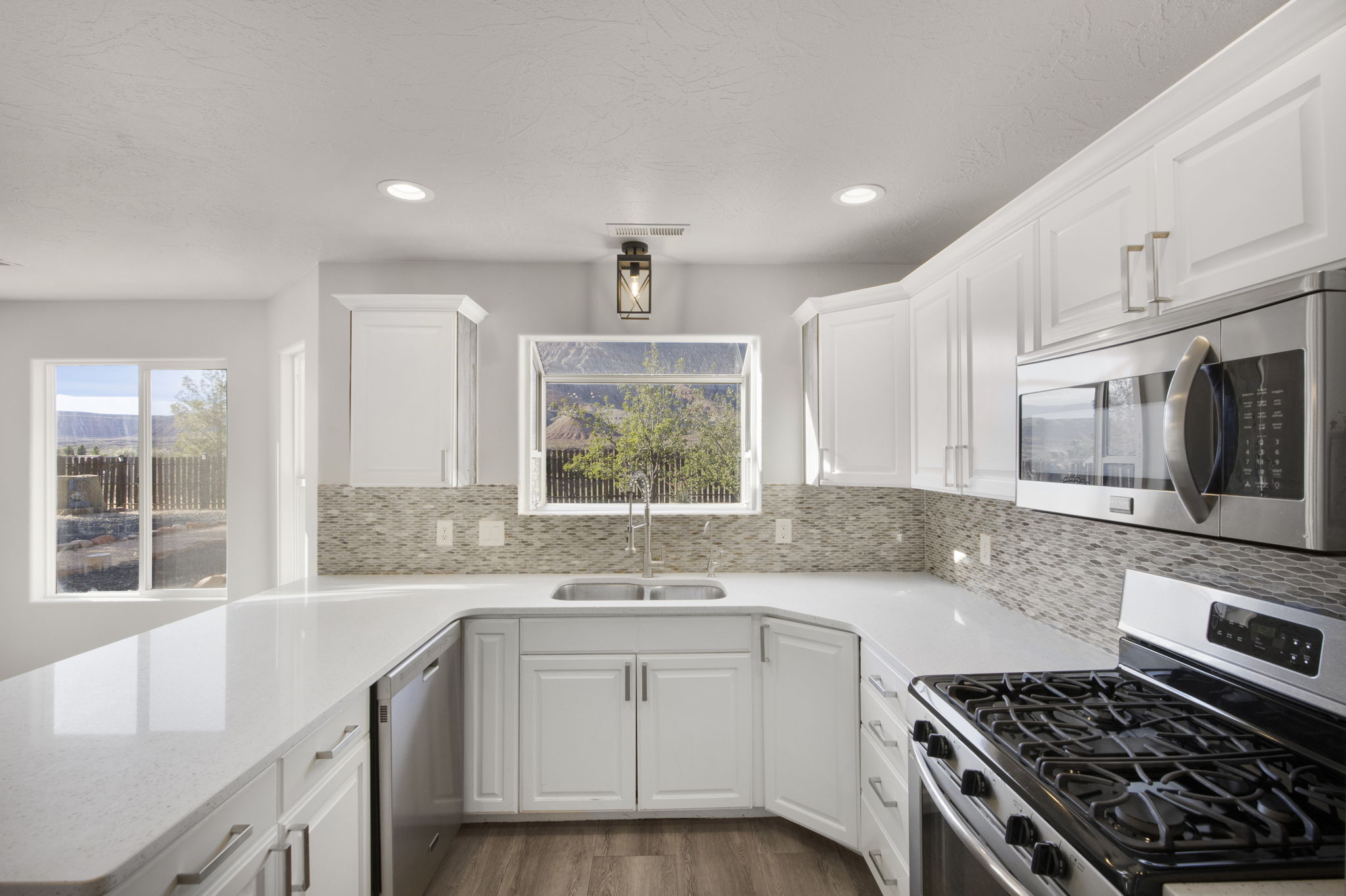 U-shaped kitchen featuring white cabinetry, light-toned countertops, and a full tile backsplash
