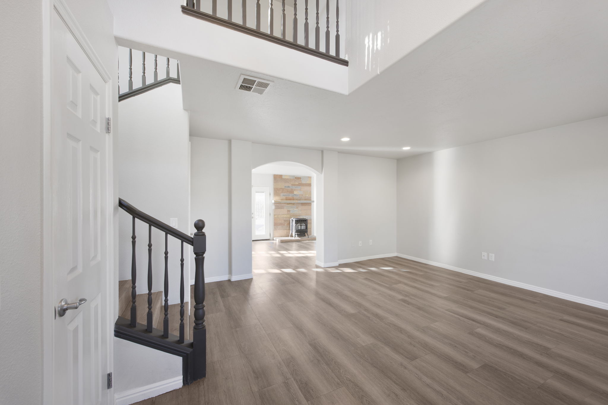 Spacious living area featuring wood-finish flooring, recessed lighting, and a two-story ceiling