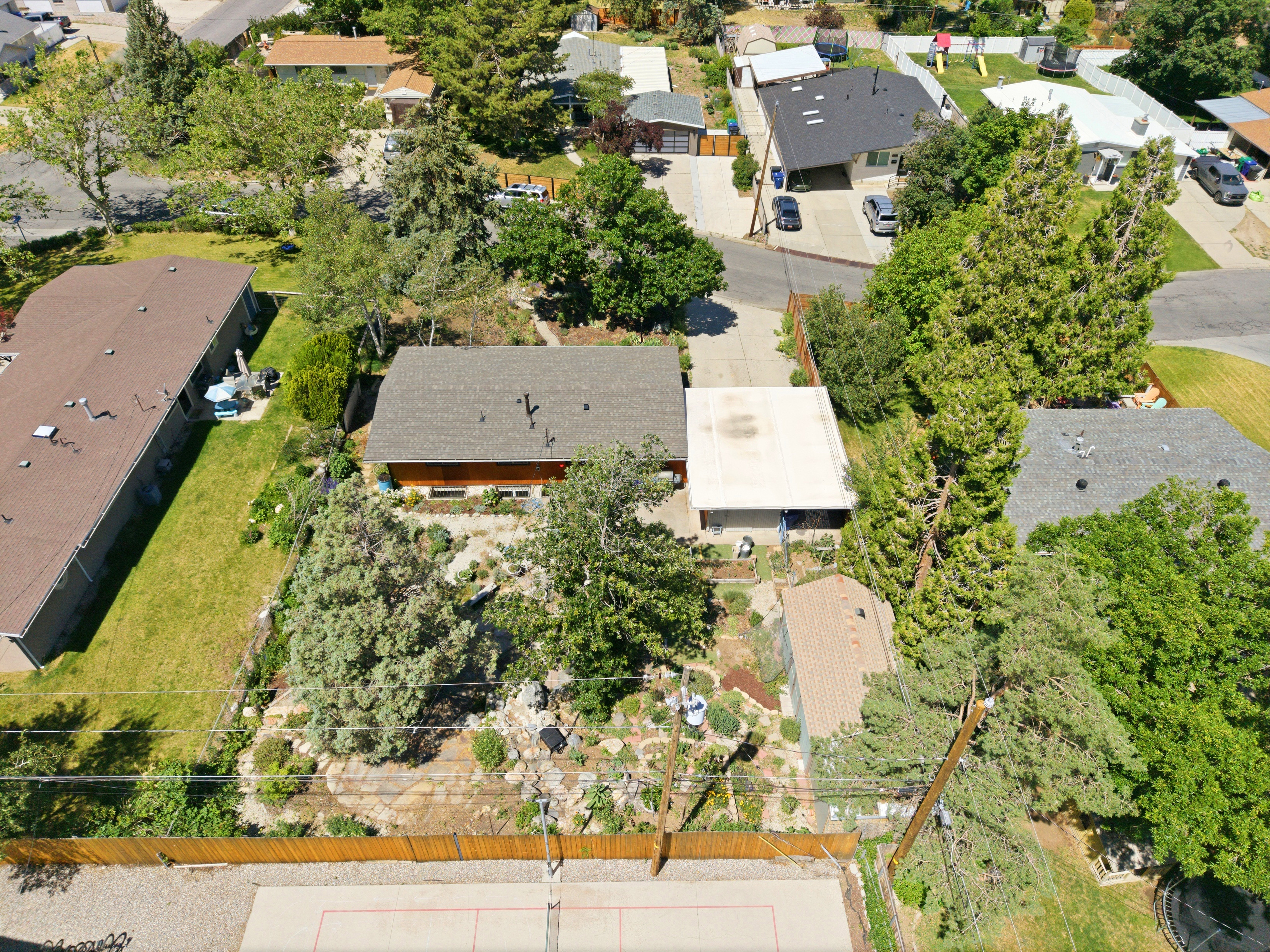 Property featuring a gabled roofline, mature landscaping, and a fenced perimeter