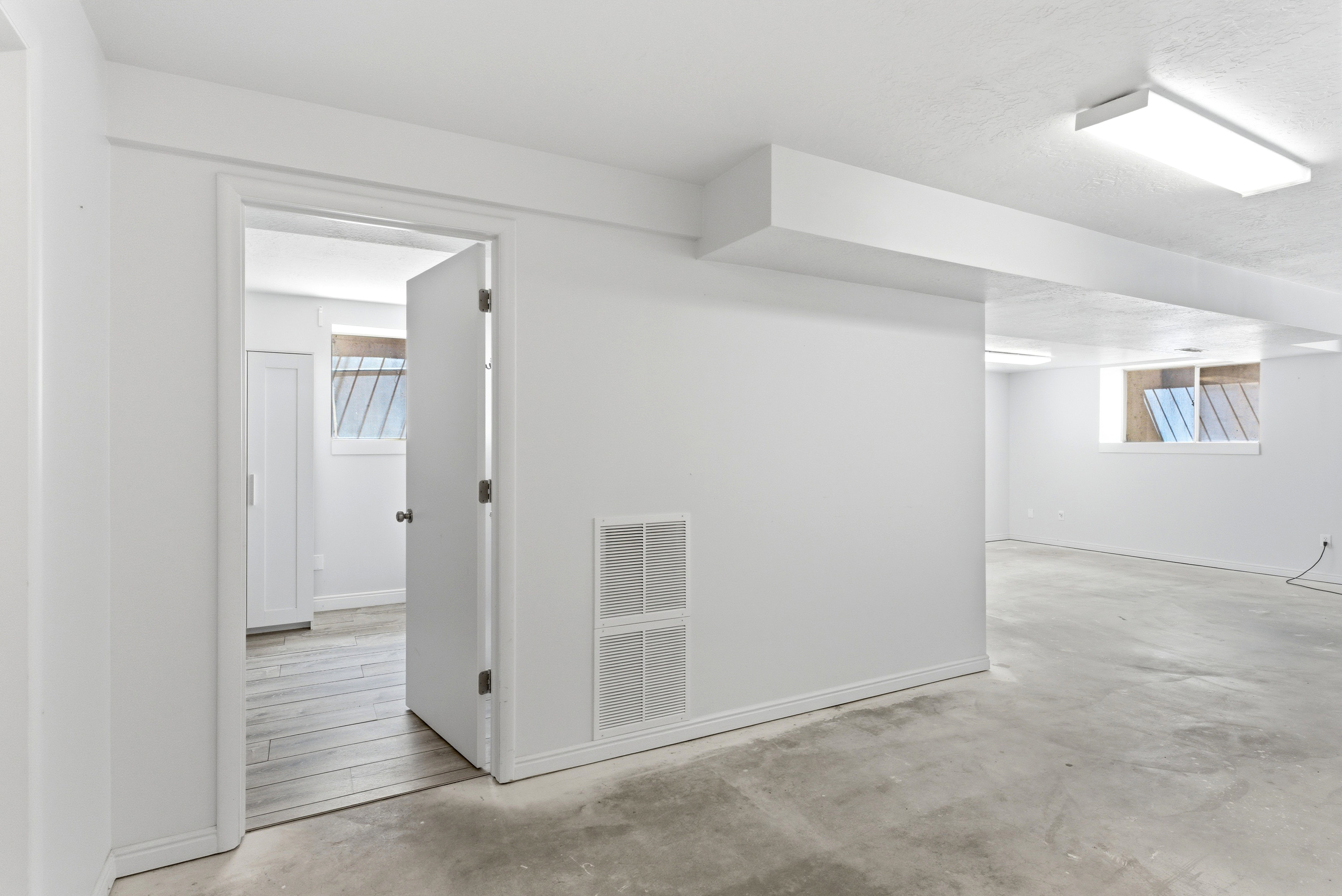 Spacious unfinished room with concrete flooring, recessed window, and white trim