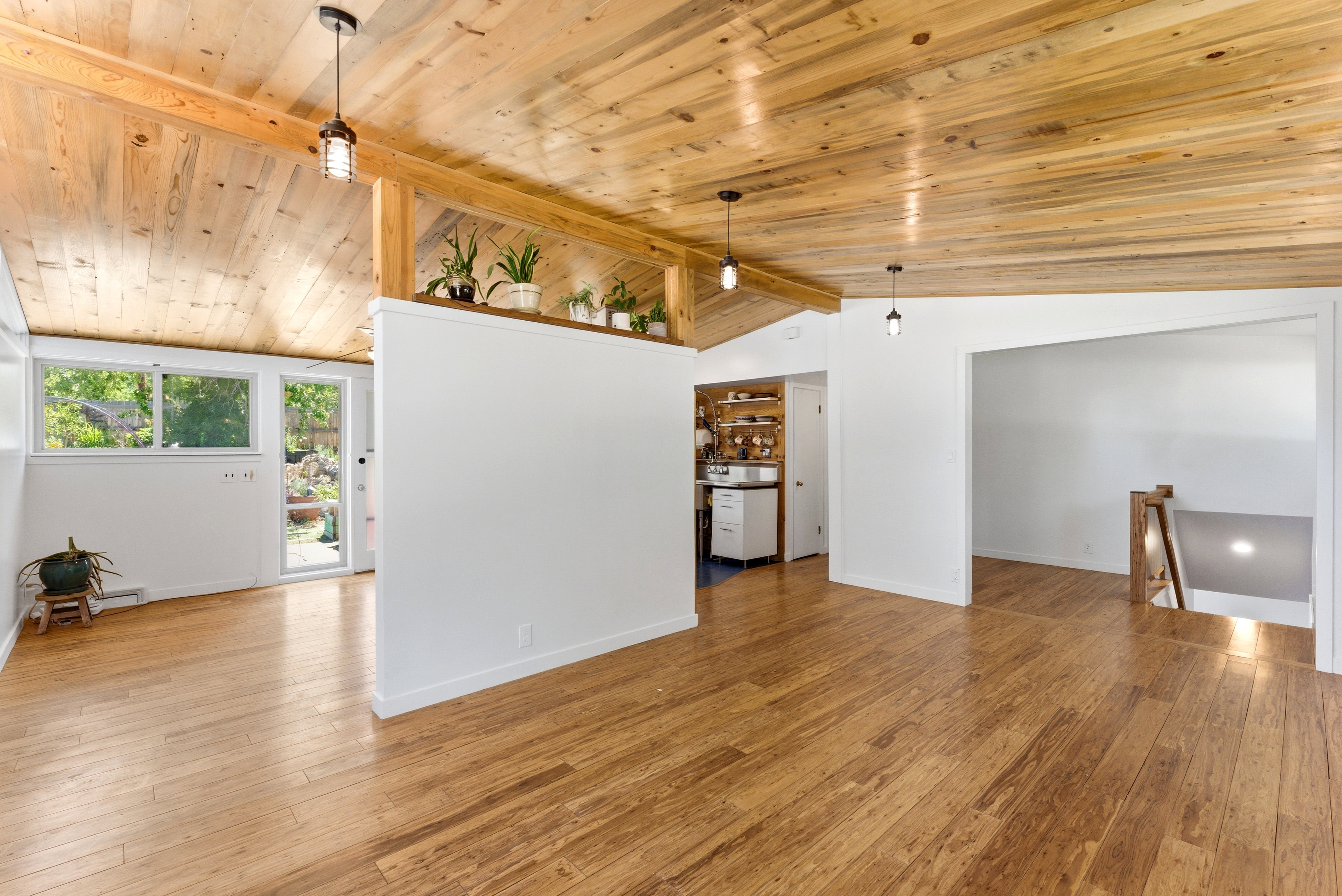 Vaulted wood-paneled ceiling with exposed beams, wood-finish flooring, and recessed wall shelving