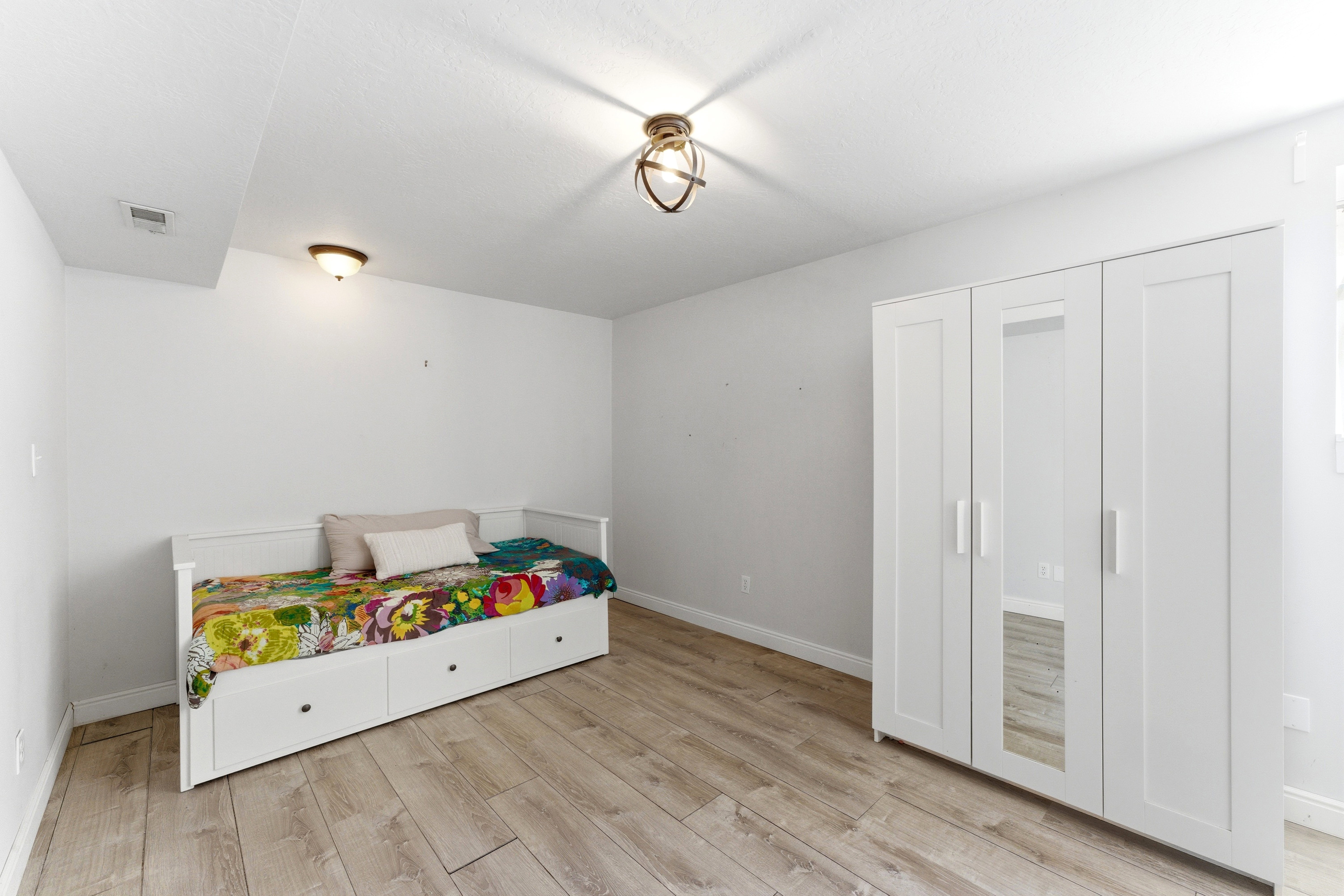 Spacious room featuring wood-finish flooring, white walls, and a recessed ceiling section