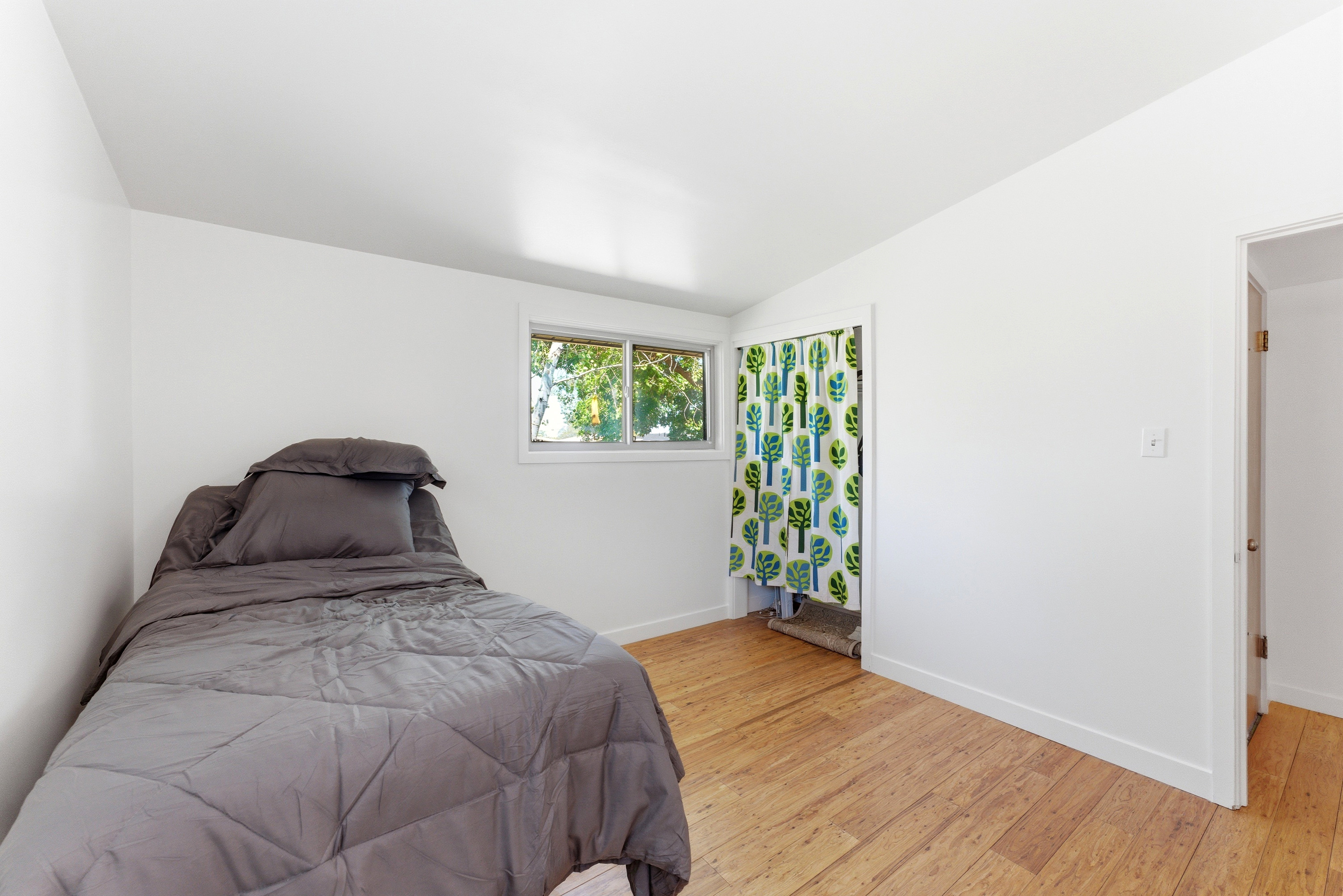 Bright room featuring light wood-finish flooring, white walls, and a window providing natural light