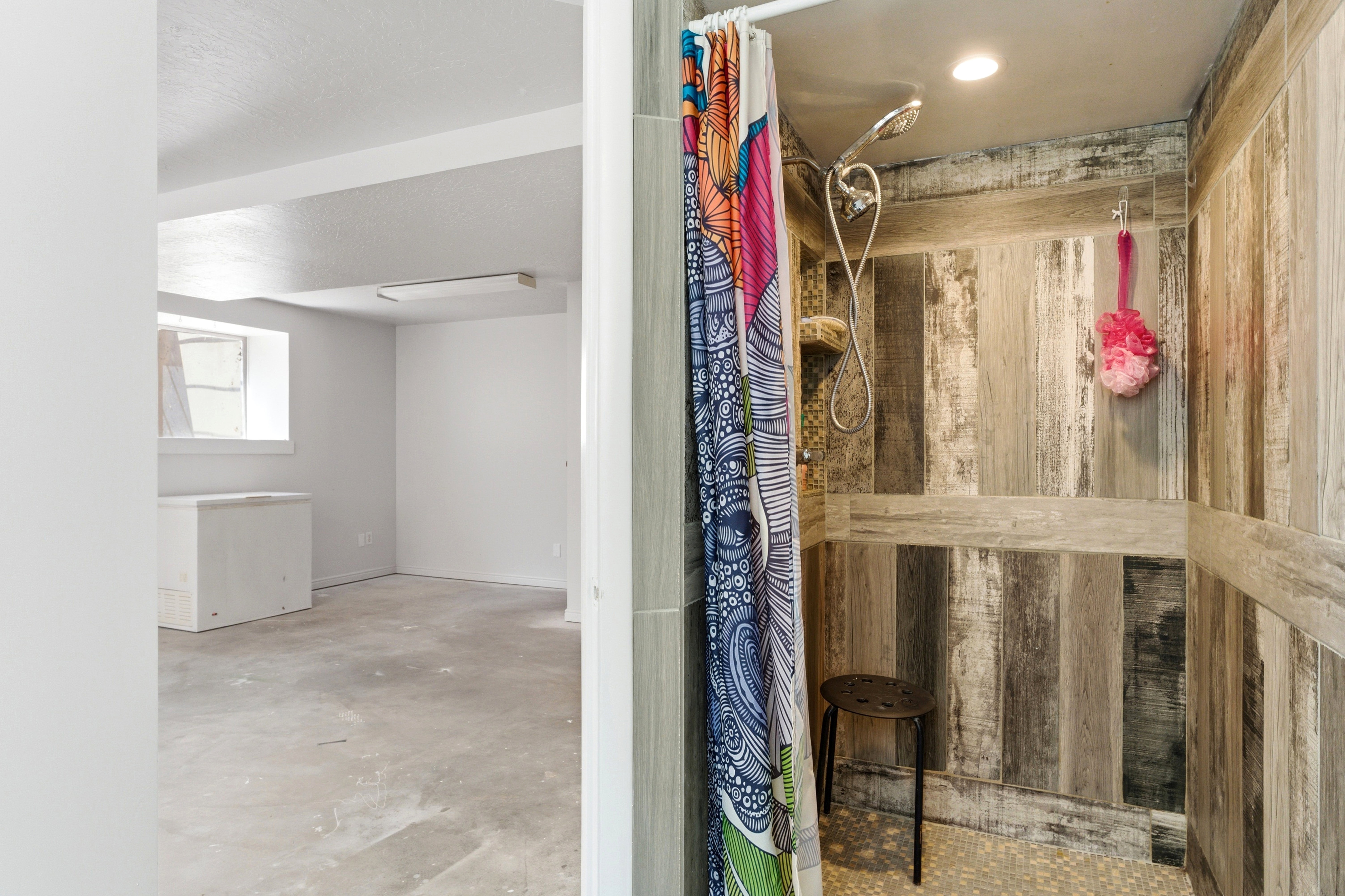 Walk-in shower featuring wood-look tile surround and a textured pebble floor