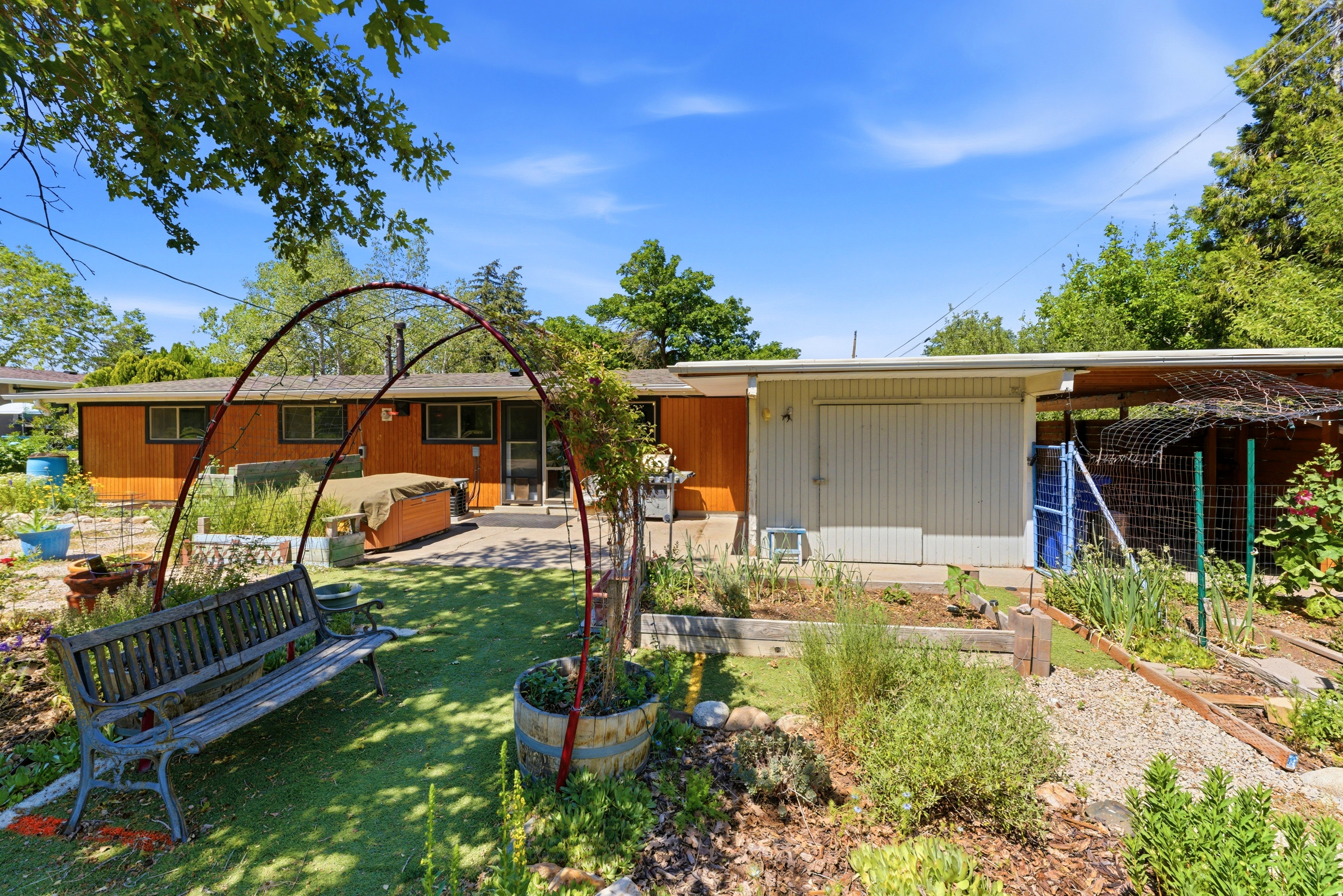 Expansive backyard featuring a manicured lawn, raised garden beds, and mature perimeter trees
