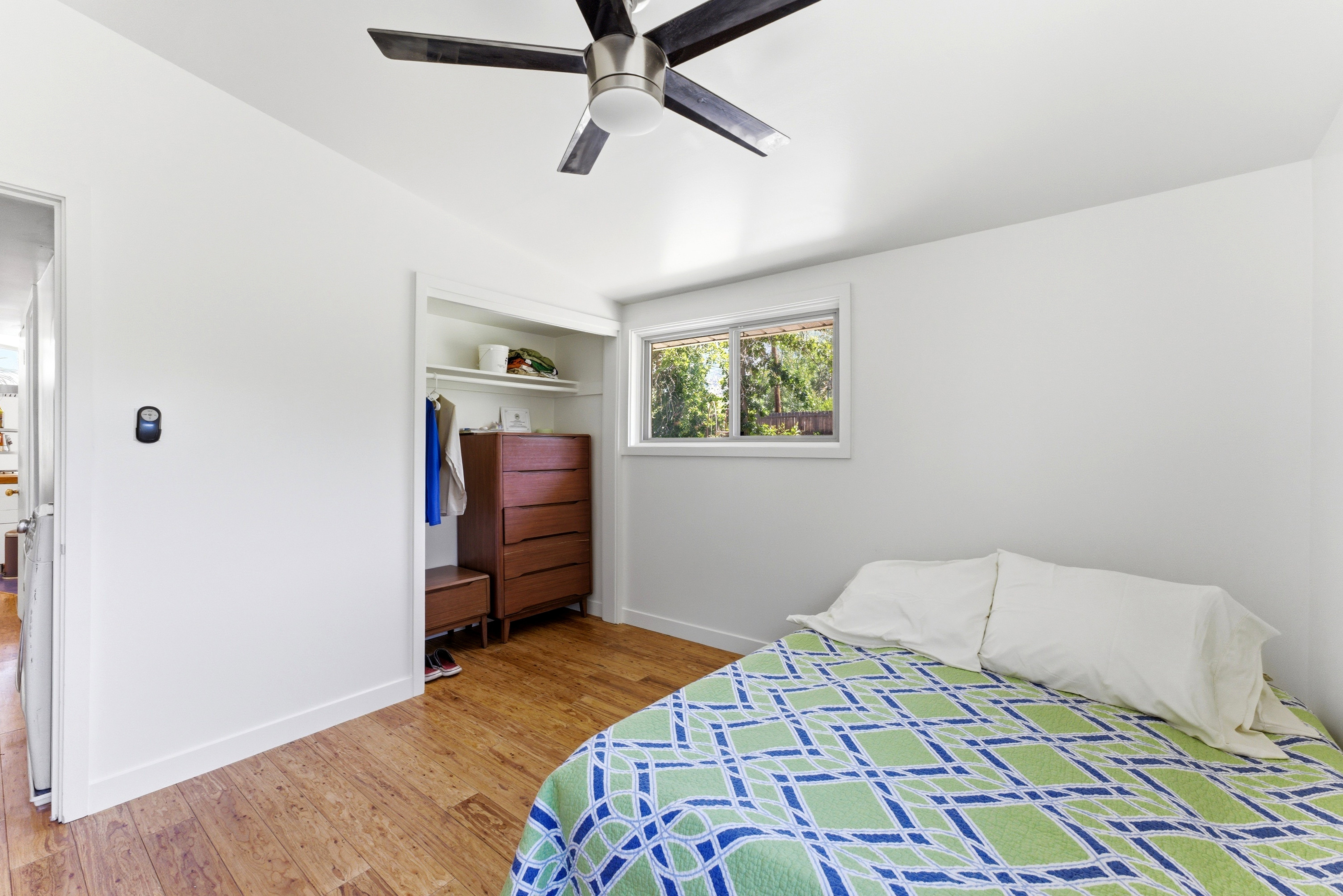 Bedroom featuring wood-finish flooring, a contemporary ceiling fan, and a built-in closet with shelving
