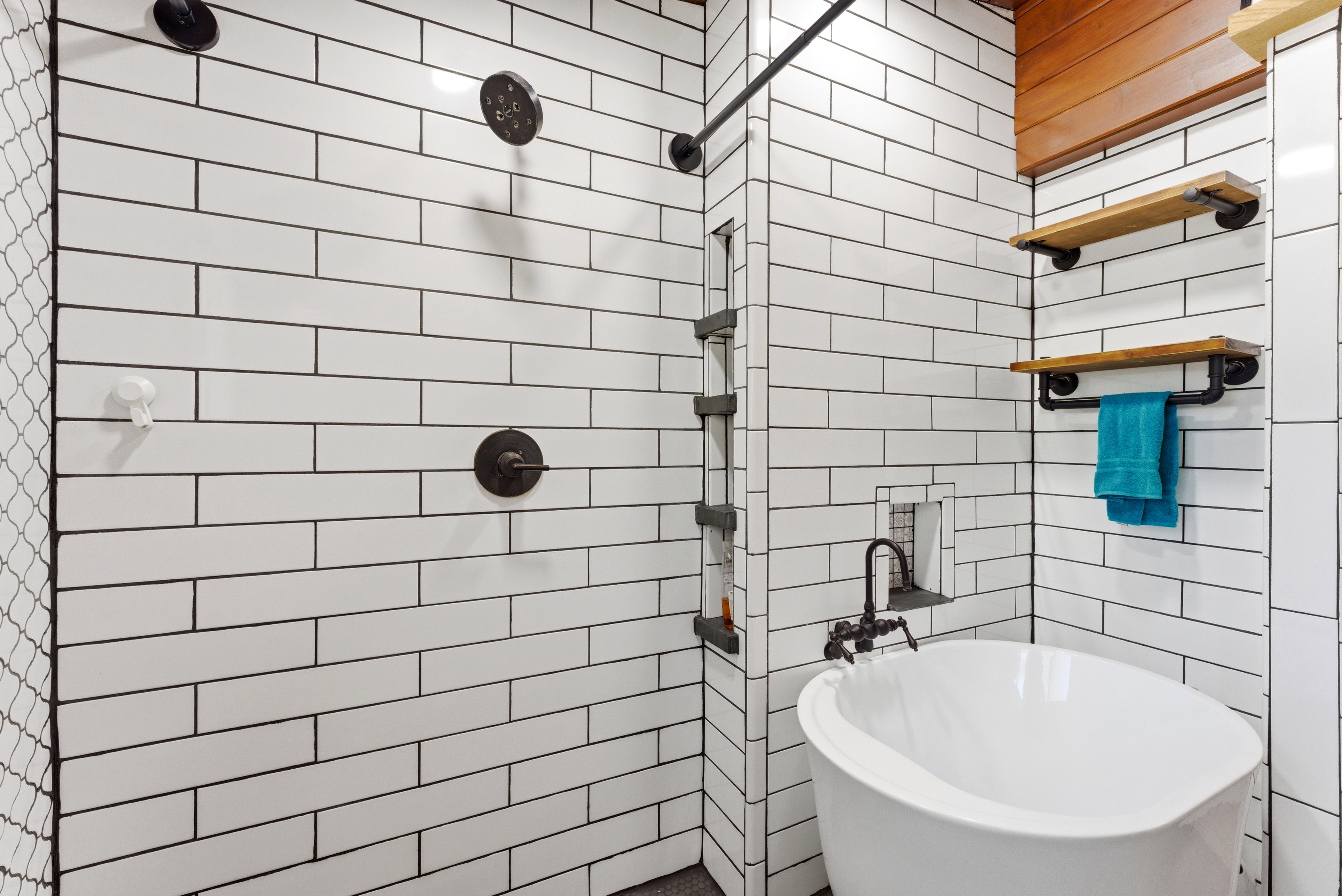 Freestanding soaking tub with a wall-mounted faucet, complemented by white subway tile walls with dark grout