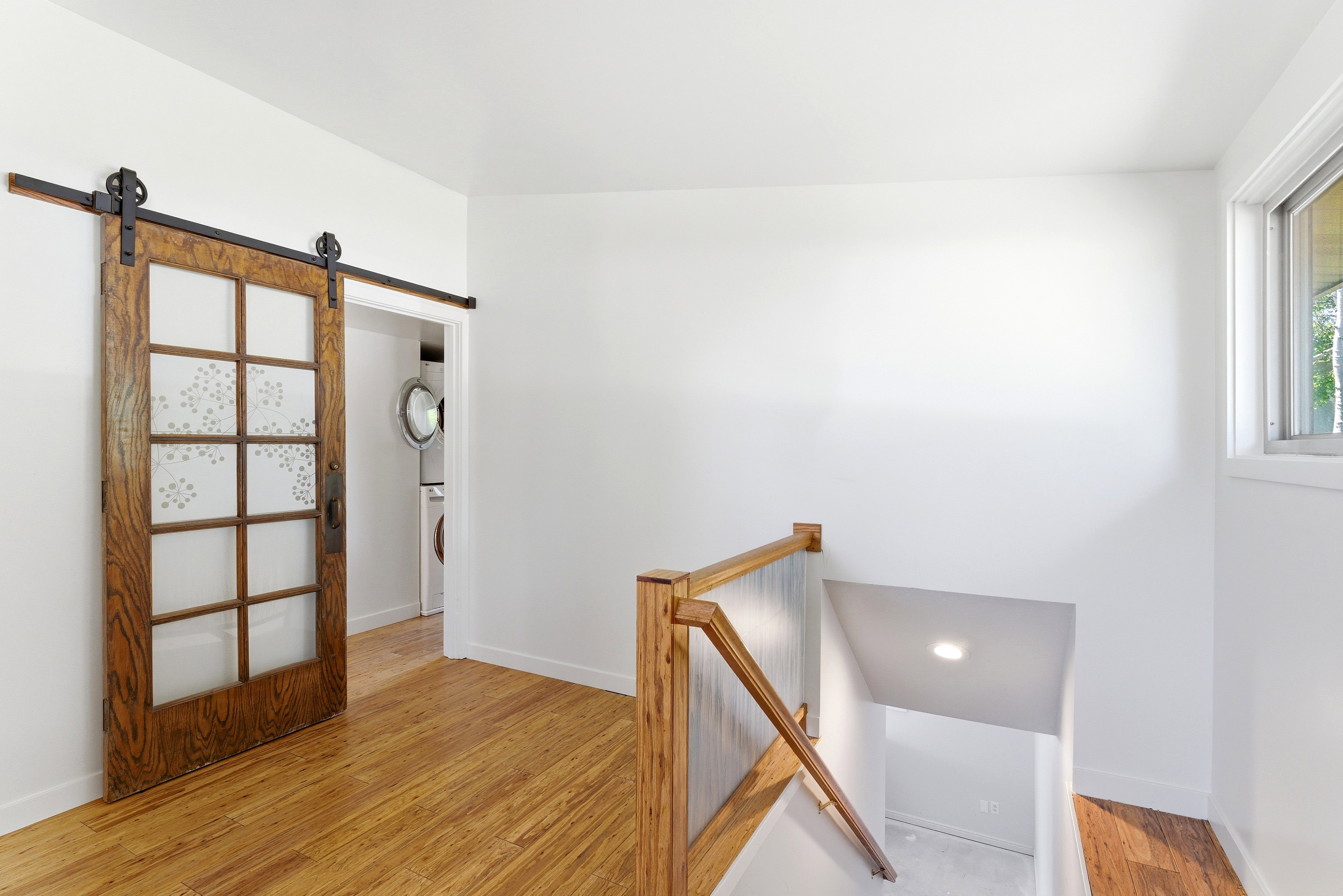 Wood-finish flooring throughout, featuring a natural wood barn door with frosted glass panels on a black iron track