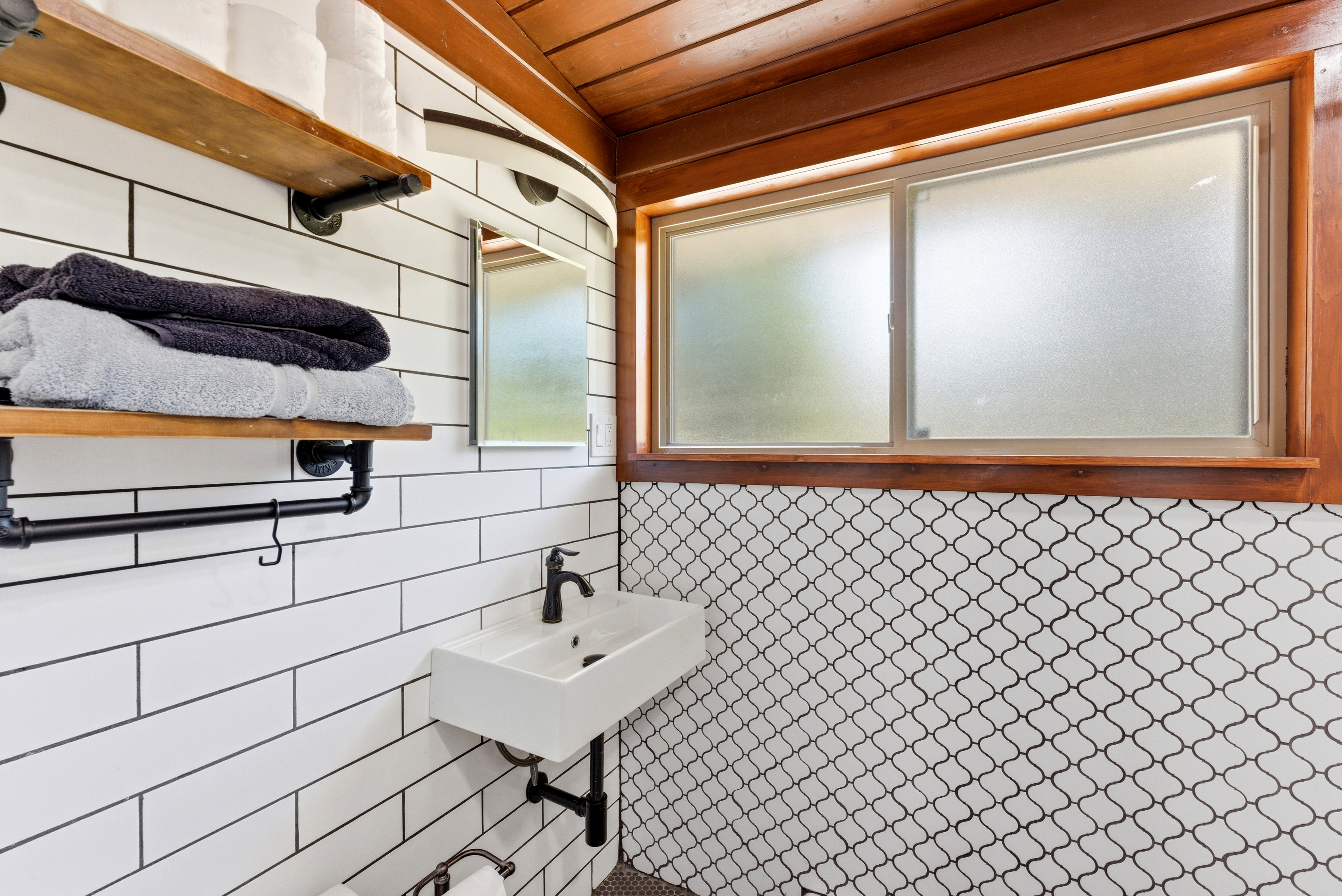 Bathroom featuring a wall-mounted rectangular sink with a matte black faucet, white subway tile walls, and a decorative arabesque tile accent