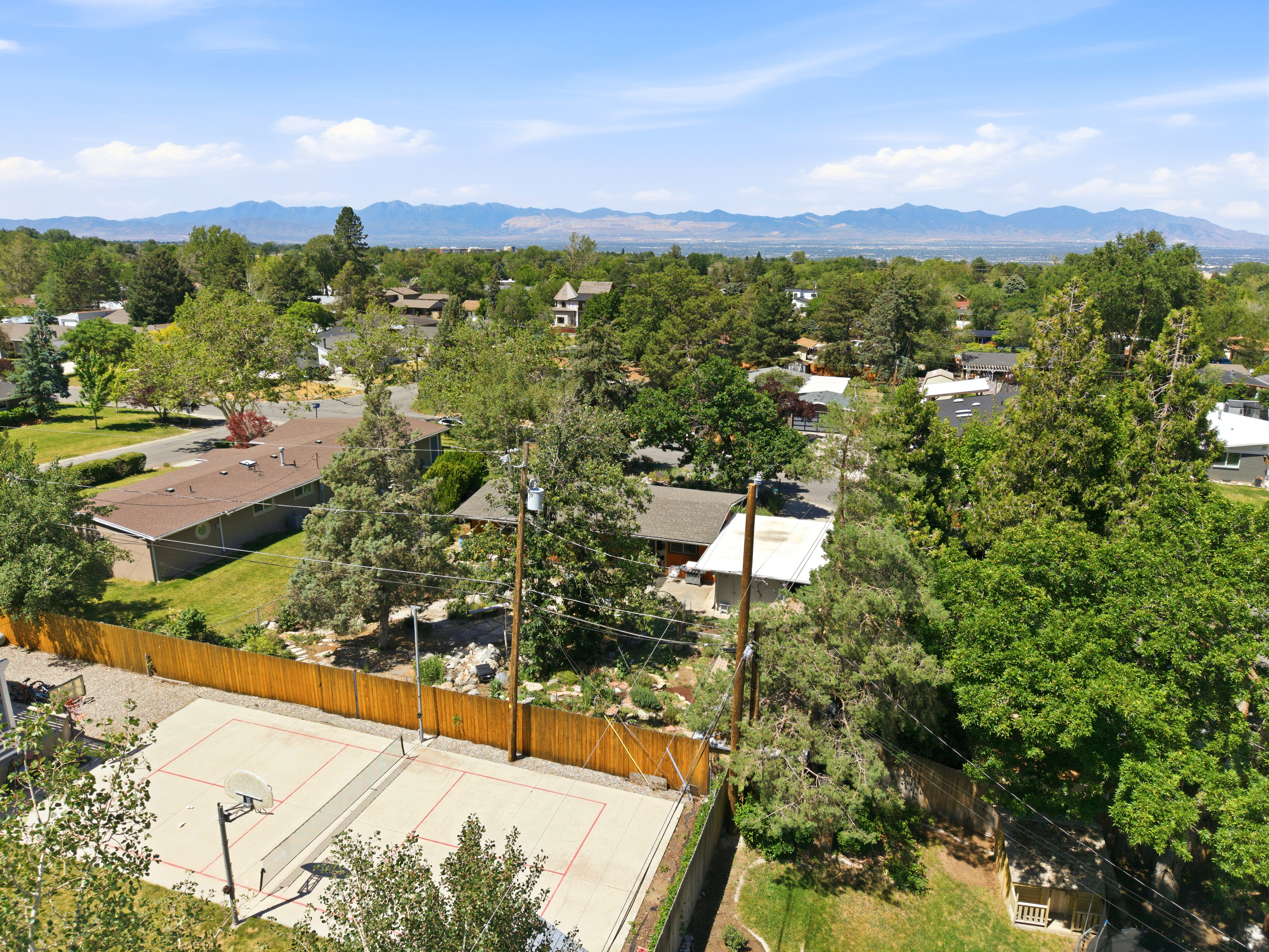 Private outdoor court featuring basketball and tennis markings, enclosed by a wooden fence